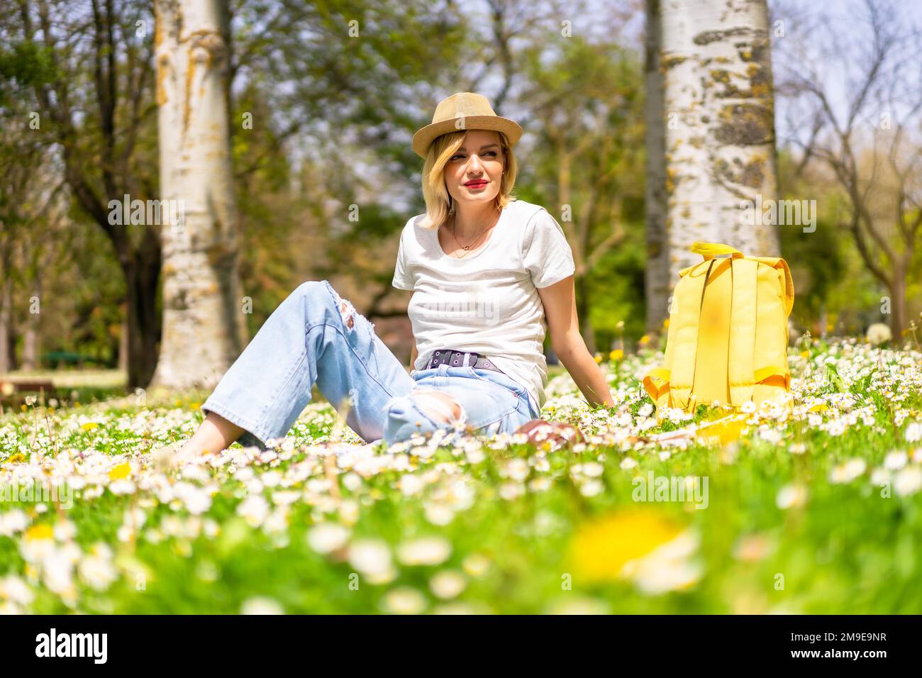 Une jeune fille blonde qui profite du printemps dans un parc de la ville, des vacances à côté de la nature et à côté des pâquerettes Banque D'Images