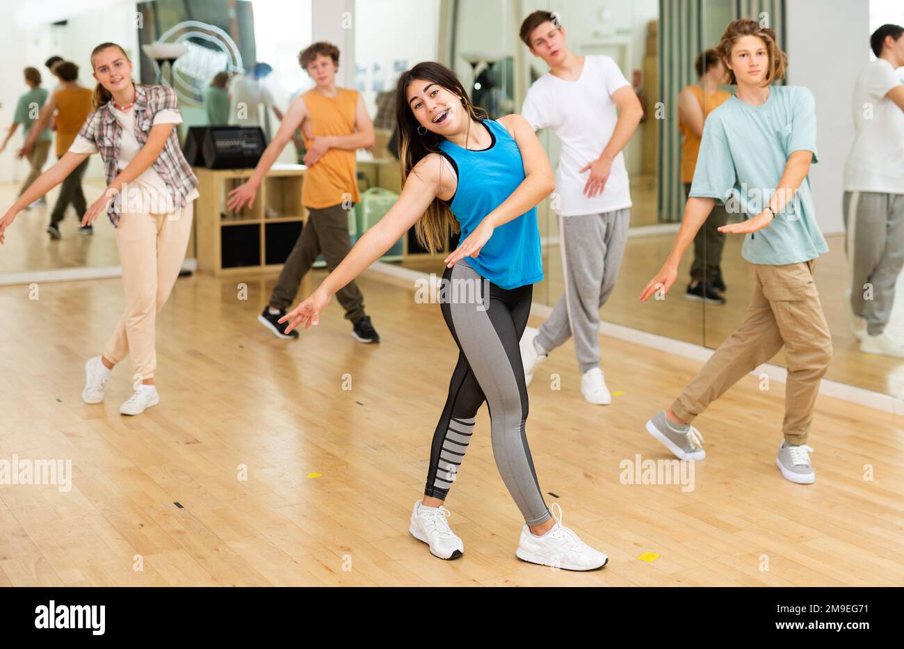 Bonne brune adolescente pratiquant la danse vigoureuse avec le groupe Banque D'Images