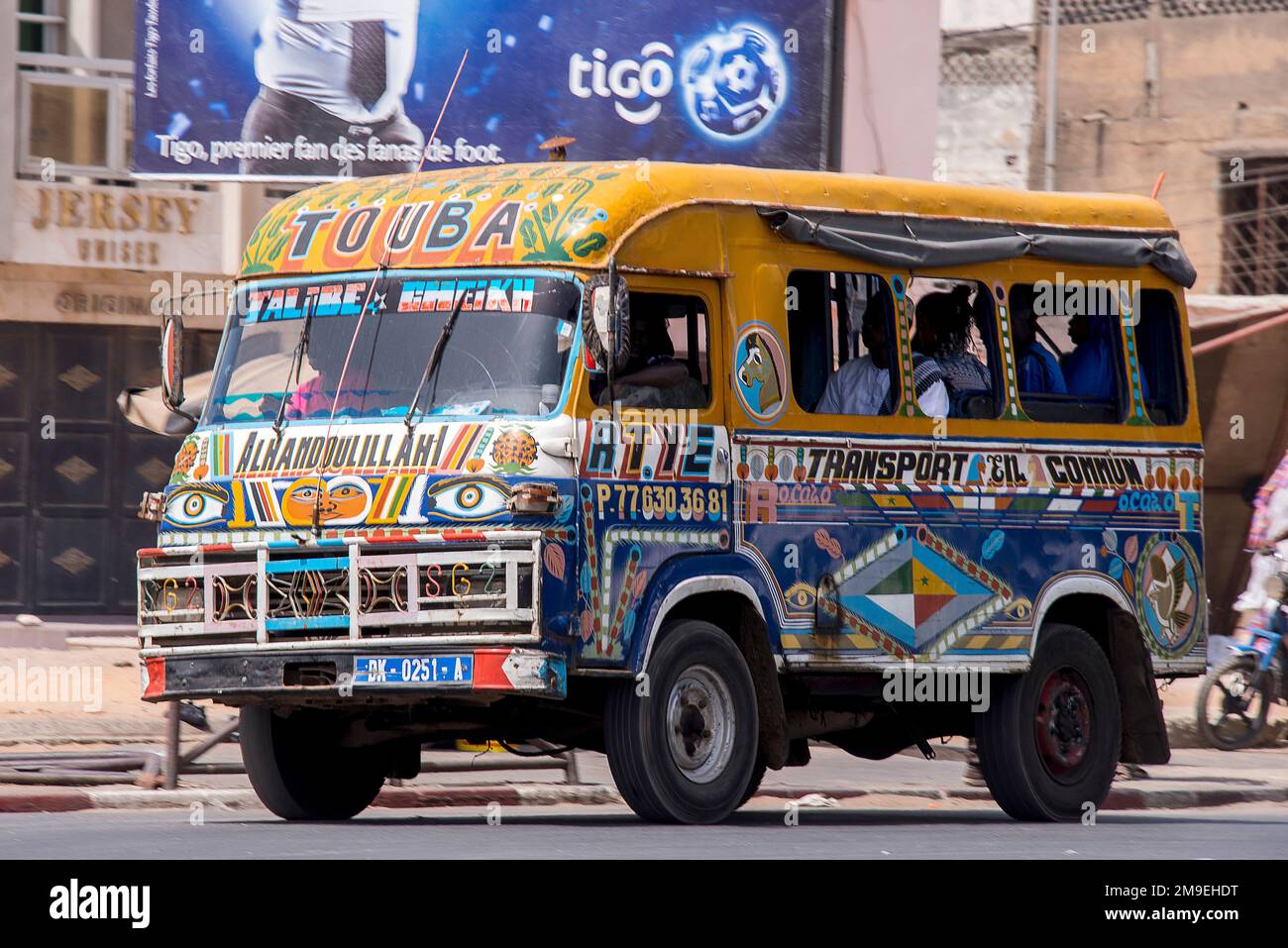 Bus multicolore typique circulant dans les rues de la ville de Dakar, Sénégal Banque D'Images