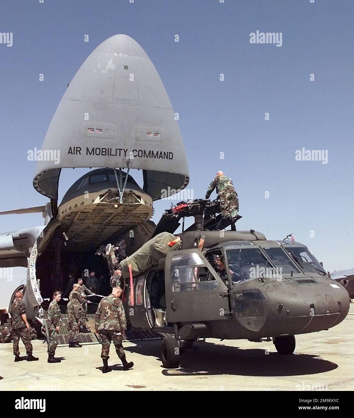 À la base aérienne du Caire Ouest, en Égypte, le personnel de l'armée aide à décharger un hélicoptère UH-60A Blackhawk d'une Galaxie de la Force aérienne C-5. Le personnel de Blackhawk et de l'Armée est arrivé en Égypte pour l'exercice BRIGHT STAR 99/00. BRIGHT STAR offre l'occasion de renforcer la coopération militaire avec les États-Unis, l'Égypte et d'autres pays de la coalition, en renforçant l'engagement conjoint en faveur de la stabilité régionale et d'autres intérêts mutuels. Les forces militaires à tous les niveaux ont les occasions uniques de renforcer les relations militaires et de se familiariser avec le personnel, l'équipement et les tactiques des forces de la coalition. Objet O Banque D'Images