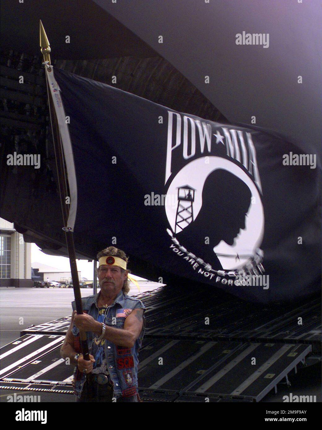 Un ancien combattant du Vietnam laisse le drapeau MIA/POW se déporter à côté de la rampe d'entrée arrière vers un Globemaster III de l'US Air Force C-17 qui a ramené les restes de ses camarades américains chez lui. La cérémonie de réparation a eu lieu à 29 août 2000, à la base aérienne de Hickam, à Hawaï. Base: Hickam Air Force base État: Hawaii (HI) pays: Etats-Unis d'Amérique (USA) Banque D'Images