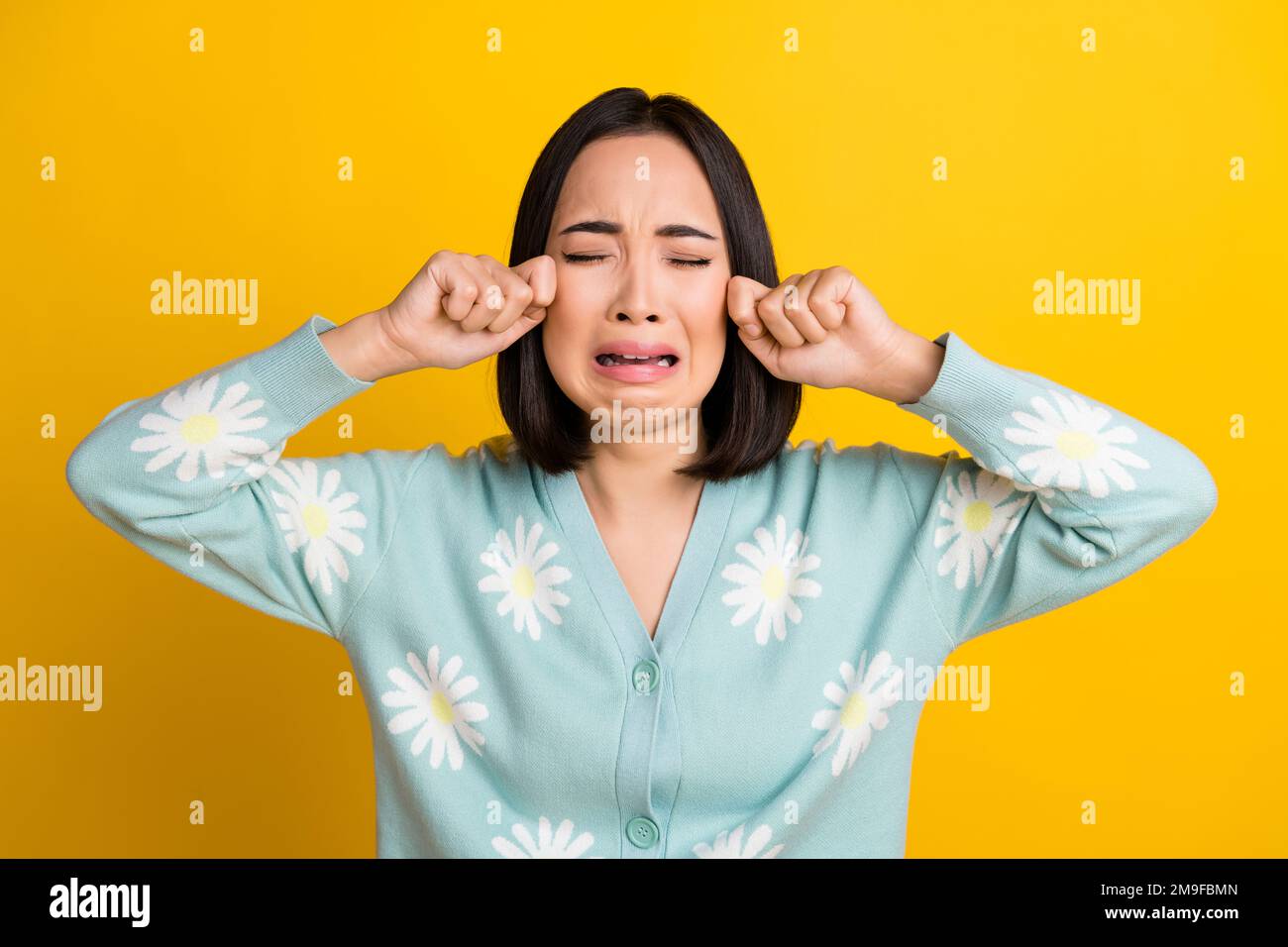 Gros plan photo de drôles stressés capricieux japonais fille porter Marguerite bleu imprimer pull pleurer les larmes problèmes isolés sur fond jaune couleur Banque D'Images