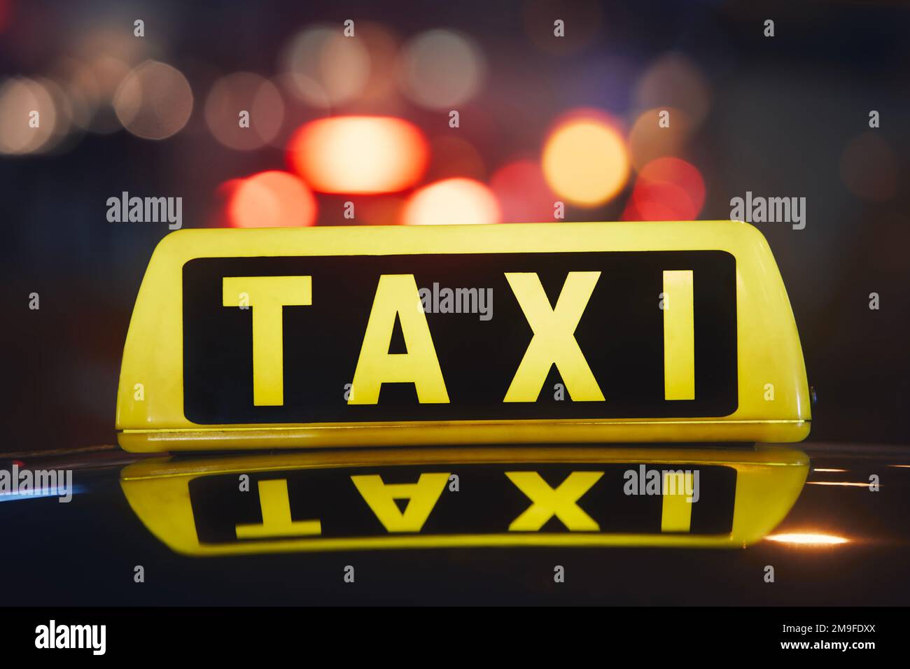 Attention sélective sur le panneau de taxi sur le toit de la voiture contre la rue animée de la ville la nuit. Banque D'Images
