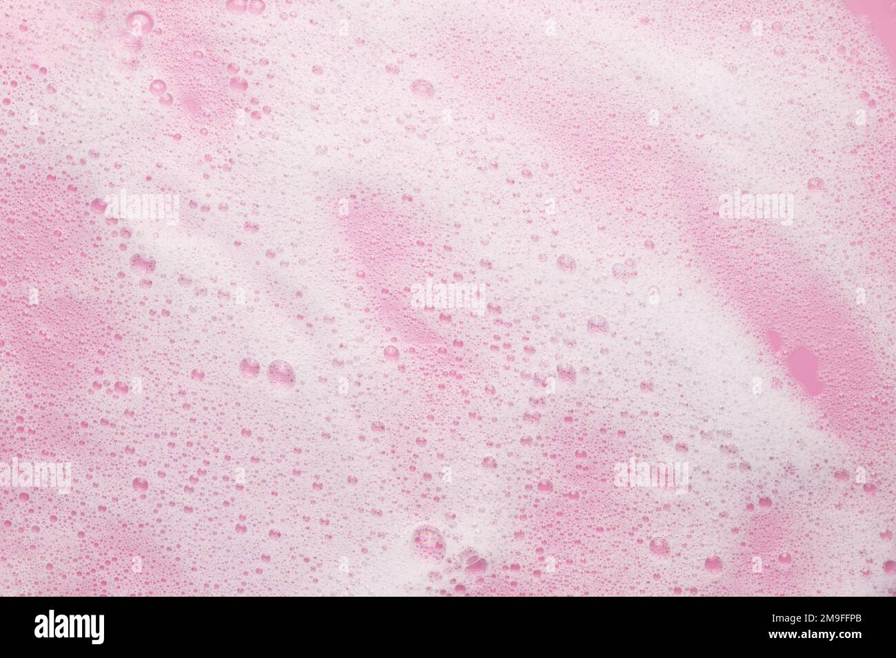 Liquide cosmétique blanc aéré moussant sur fond rose. Mousse de bain, mousse, shampooing. Concept de beauté ou de soins de la peau. Banque D'Images