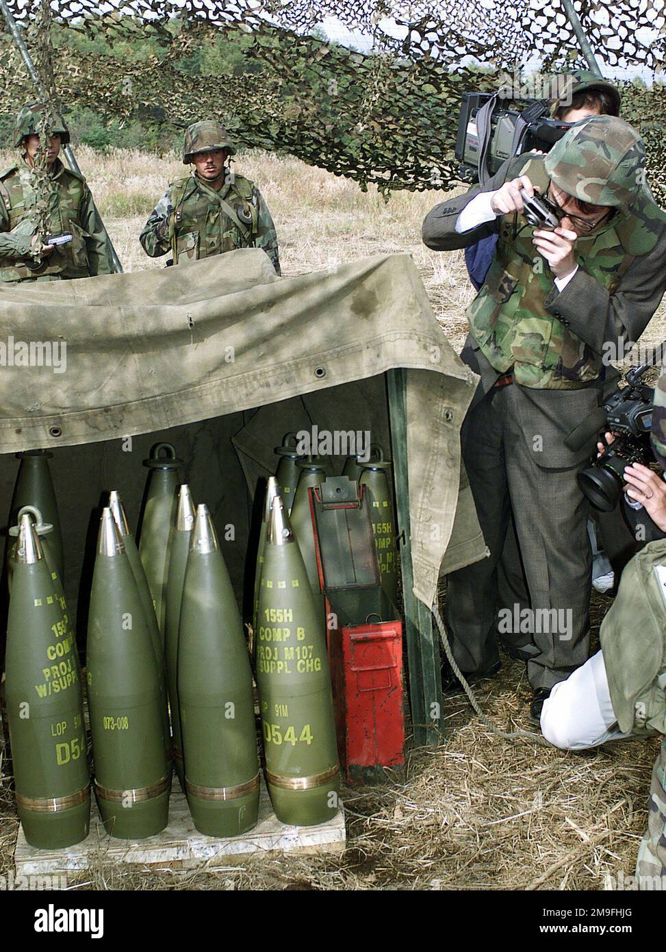 Des membres des médias japonais photographient les M107 155mm projectiles explosifs de haut niveau, tandis que les Marines des États-Unis du 3rd Bataillon, 12th Marine Regiment, 3D Marine Division, se préparent à tirer le feu de l'Howitzer tracté moyen M198 155mm à la position 10 du canon, East Camp Fuji, Japon. La zone d'entraînement fait partie de la séance de déplacement de neuf jours de tir de l'unité, conçue pour améliorer les compétences de spécialité militaire dans le domaine de l'artillerie. Sujet opération/série: FOAL EAGLE 2000 base: Base du corps marin, Camp Fuji État: Honshu pays: Japon (JPN) Banque D'Images