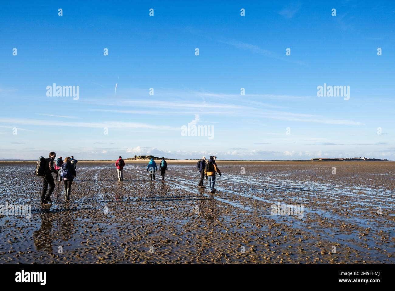 Groupe de personnes marchant vers l'île de Little Eve sur la route de l'île Hilbre dans l'estuaire de Dee à marée basse de West Kirby, la péninsule Wirral, Merseyside, Angleterre Banque D'Images