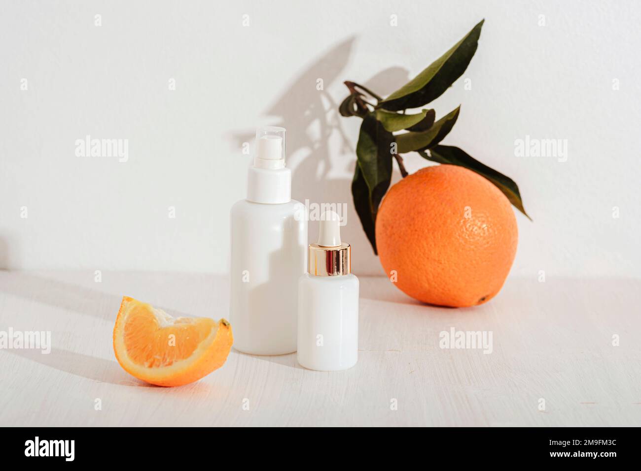 Flacons de sérum à usage cosmétique et fruits orange sur fond blanc. Concept de cosmétiques naturels, maquette. Banque D'Images