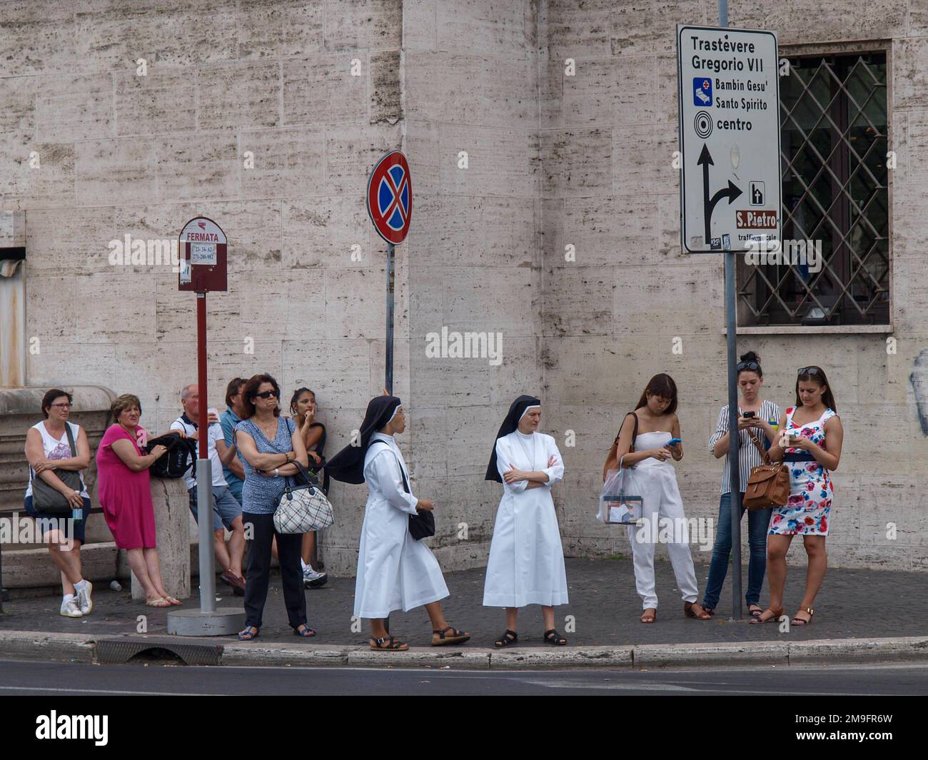 Deux religieuses sont debout parmi un groupe de personnes à l'arrêt des transports publics dans la rue de Rome Banque D'Images