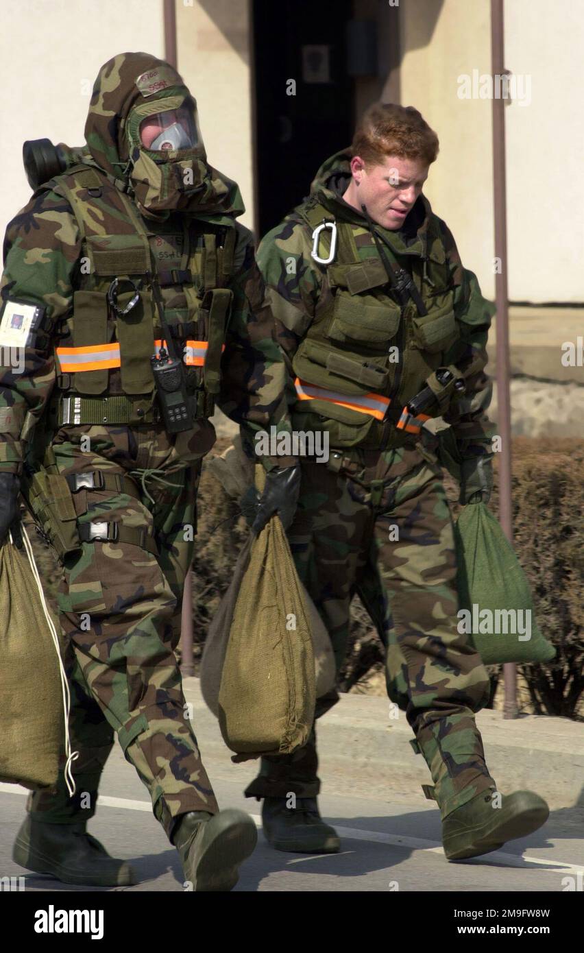 LE sergent d'ÉTAT-MAJOR de LA Force aérienne AMÉRICAINE John Lawson et L'AVIATEUR PRINCIPAL Randy Bayne, du 51st e Escadron de génie civil, à la base aérienne d'Osan, en République de Corée, transportent des sacs de sable pour peser une munitions non explosée au cours d'une inspection de préparation opérationnelle. SSGT Lawson porte un équipement de niveau 4 (MOPP-4) pour la posture de protection orientée mission et SRA Bayne est au MOPP-2. Base: Osan Air base pays: République de Corée (KOR) Banque D'Images