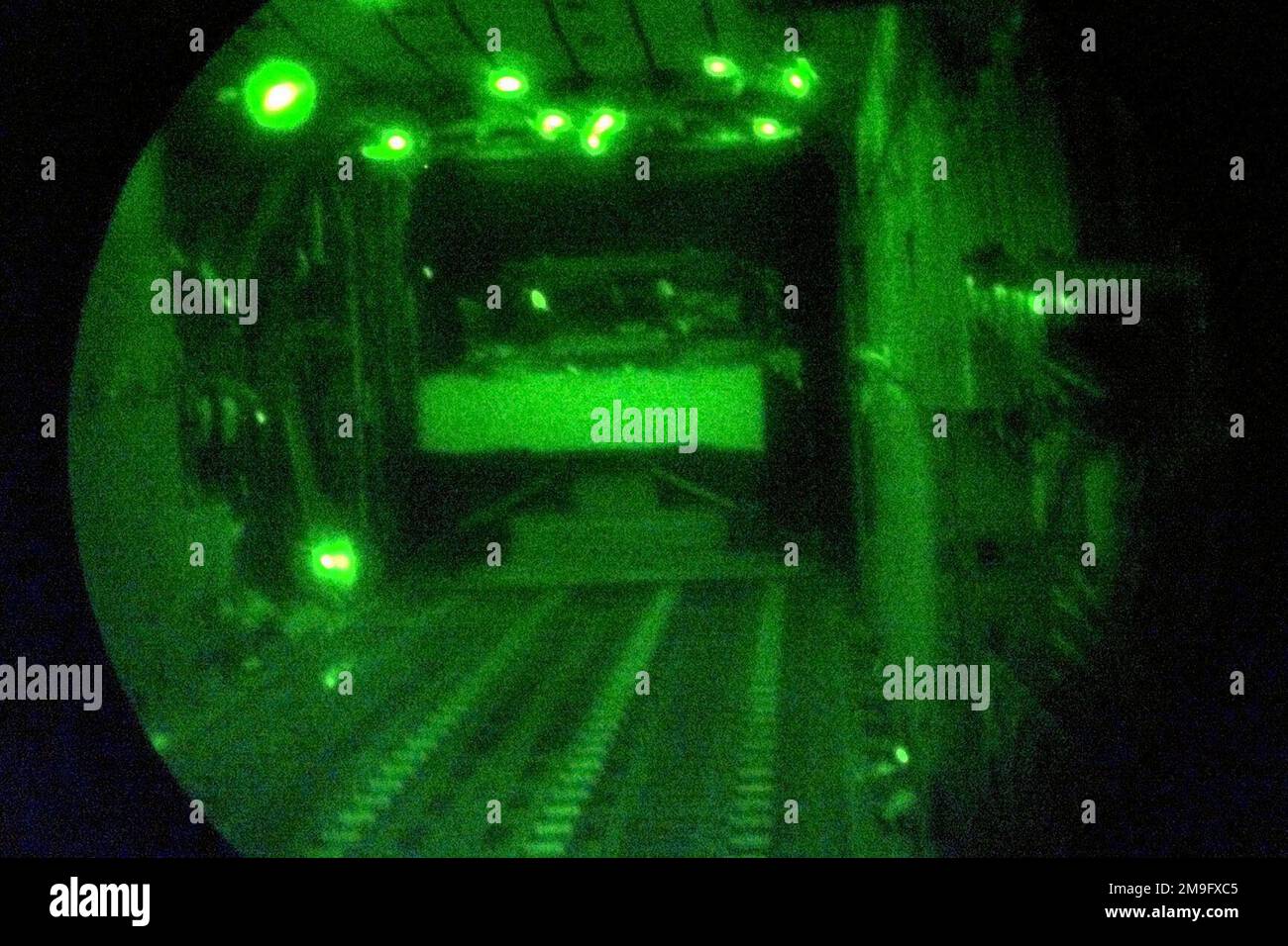 Des marchandises palettisées sortent de la porte arrière d'un avion Hercules C-130 de la US Air Force pendant une chute d'air qui fait partie de l'exercice NORTHERN EDGE. L'image est photographiée à l'aide d'un objectif de vision nocturne. Des marchandises palettisées sortent de la porte arrière d'un avion Hercules C-130 de la US Air Force pendant une chute d'air qui fait partie de l'exercice NORTHERN EDGE. L'image est photographiée à l'aide d'un objectif de vision nocturne. Banque D'Images