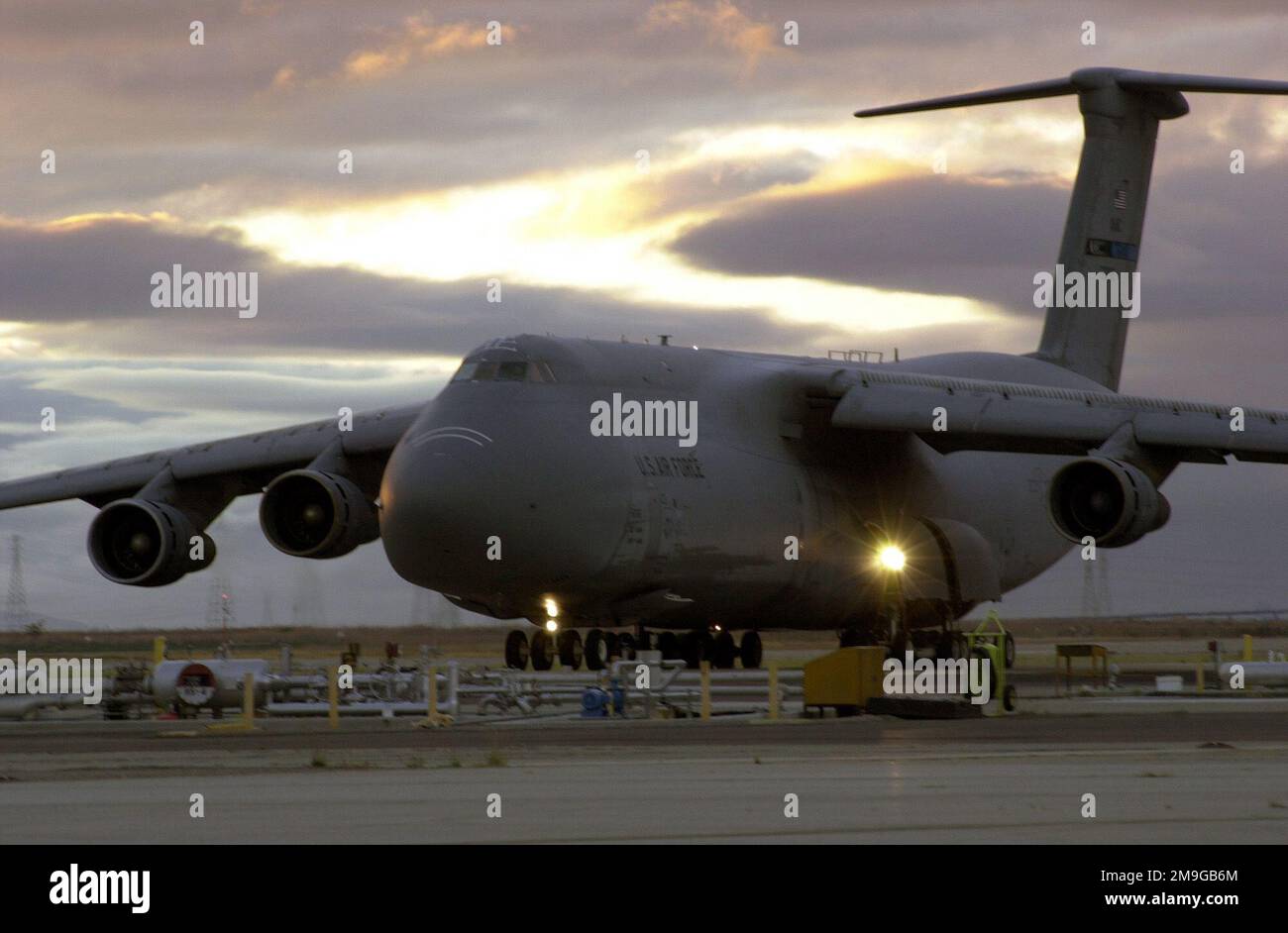Une galaxie C-5B de la Réserve de l'Armée de l'Air passe devant la station-service à la lumière du soir à l'aérodrome fédéral de Moffett, Mountain View, Californie. Capable de contenir 51 150 gallons de carburant, un C-5 avec une charge de 270 000 livres peut voler 2 150 milles marins, décharger, et voler vers une deuxième base à 500 milles marins de distance. Base: Moffett Federal Air Field État: Californie (CA) pays: États-Unis d'Amérique (USA) scène Major Command montré: 129th Rescue Wing Banque D'Images