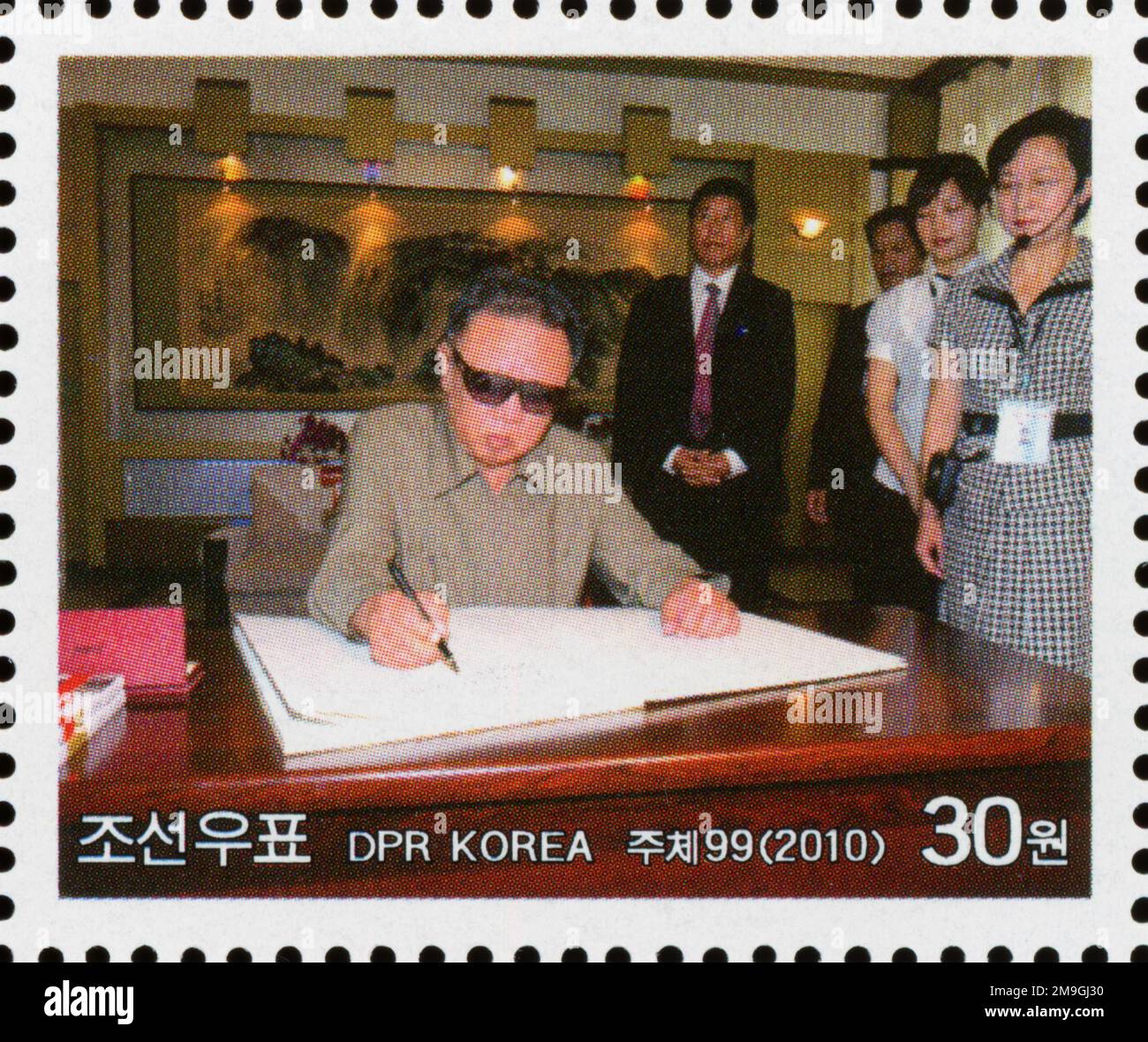 Timbre-poste nord-coréen de 2010 représentant le dirigeant Kim Jong-il signant un document lors d'une visite officielle en Chine. Banque D'Images