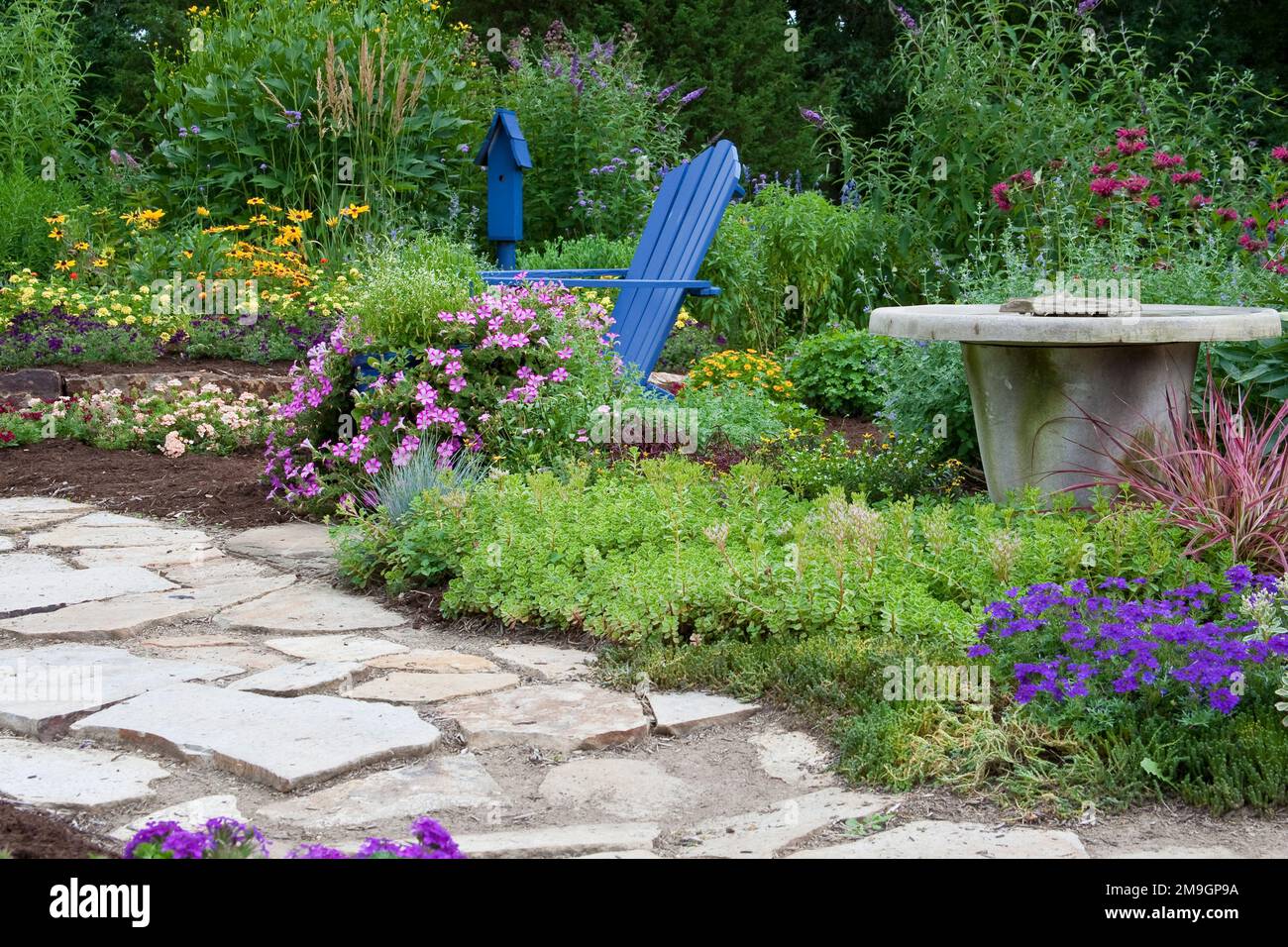 Jardin de fleurs bleu 63821-21904 avec chaise Adirondack, bain d'oiseaux et bleu nichoir. Butterfly Buissons, Peach & Purple verveines, jaune Lantana (Lantan Banque D'Images