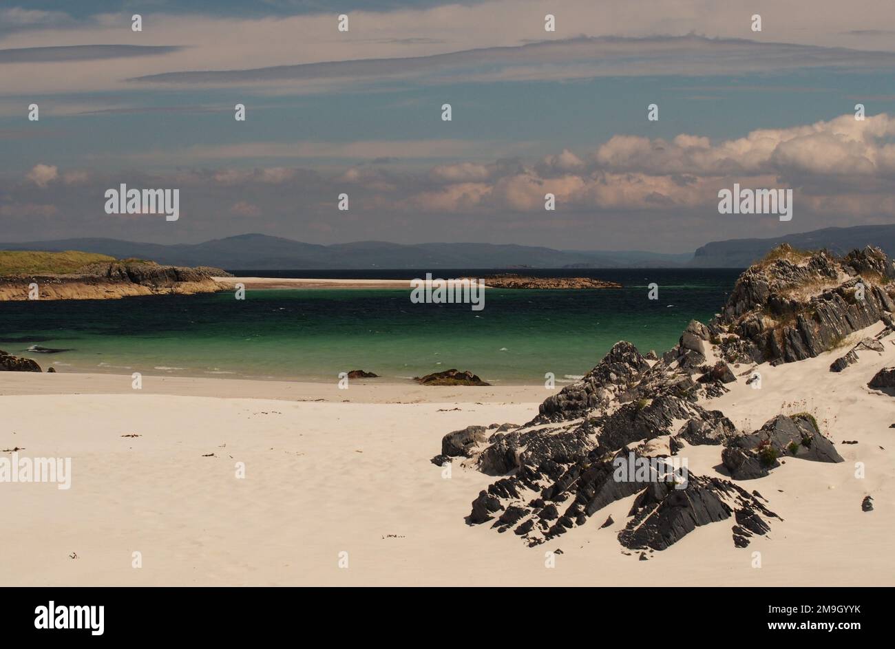 White Strand of the Monk's Beach, Iona, Écosse, Royaume-Uni, lors d'une journée ensoleillée d'été, montrant le sable blanc, les rochers escarpées et la mer colorée et vibrante Banque D'Images