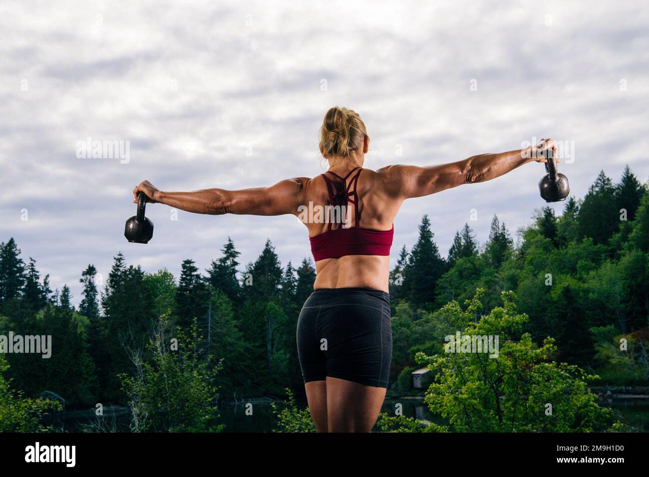 Femme s'exerçant à l'extérieur avec kettlebells, Bainbridge Island, Washington, États-Unis Banque D'Images