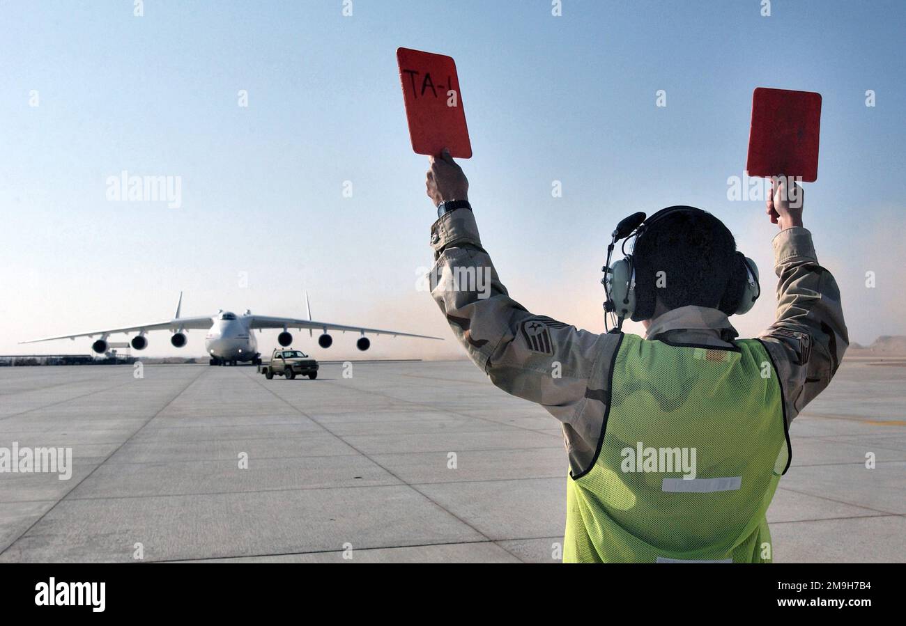 Un chef d'équipe de l'Armée de l'Air américaine Transient Alert (TA) de l'aile expéditionnaire aérienne (AEW) de 405th dirige un Mriya ukrainien Antonov AN-225, le plus grand avion du monde, vers son emplacement de stationnement pendant l'opération ENDURING FREEDOM. Objet opération/série : BASE DE LIBERTÉ DURABLE : base aérienne de Thumbait pays : Oman (OMN) Banque D'Images