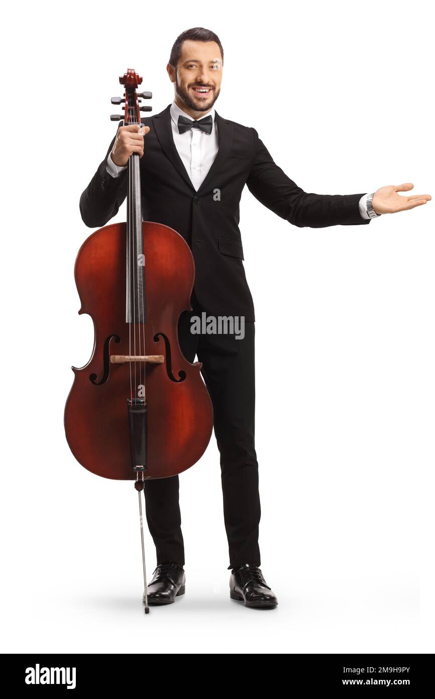 Portrait en longueur d'un jeune artiste masculin posant avec un violoncelle et montrant avec la main isolée sur fond blanc Banque D'Images