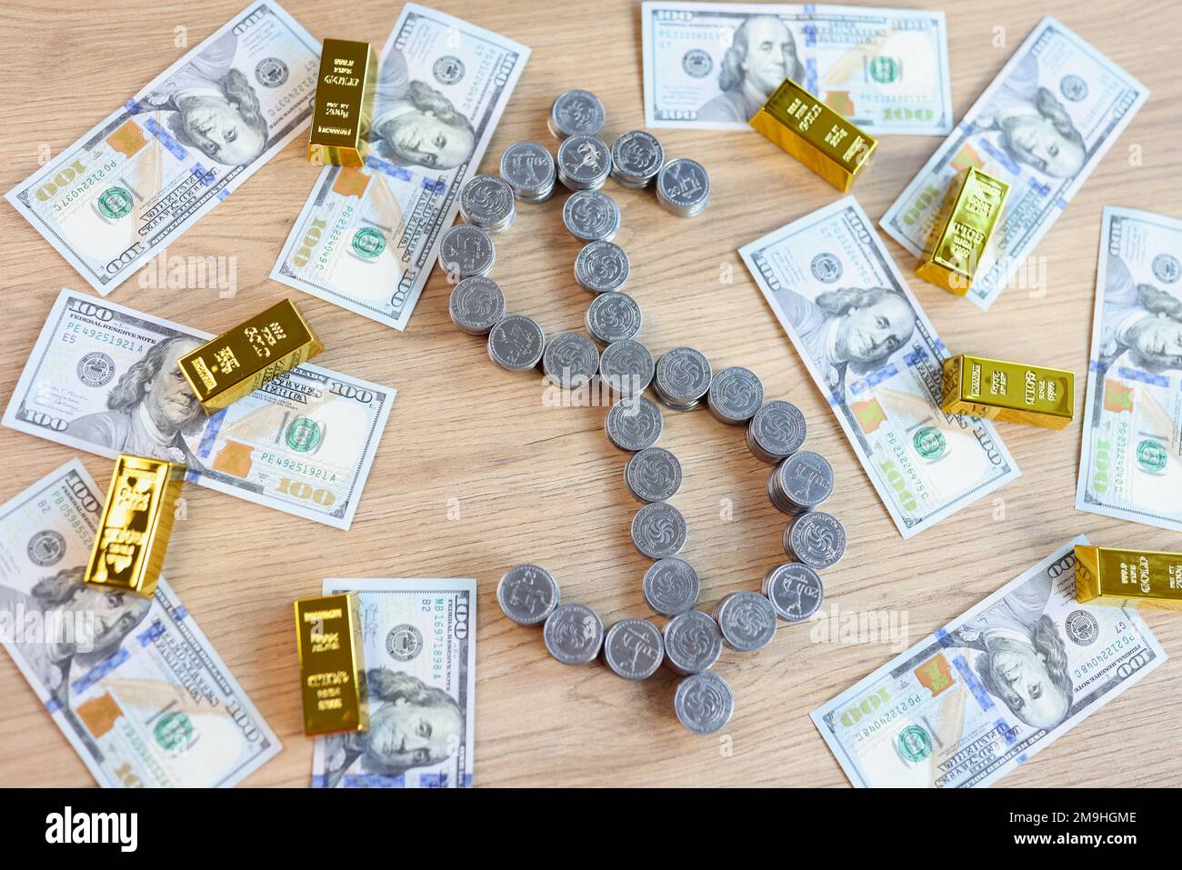Pièces d'argent en forme de symbole dollar et barres d'or avec billets en dollars sur table en bois. Banque D'Images