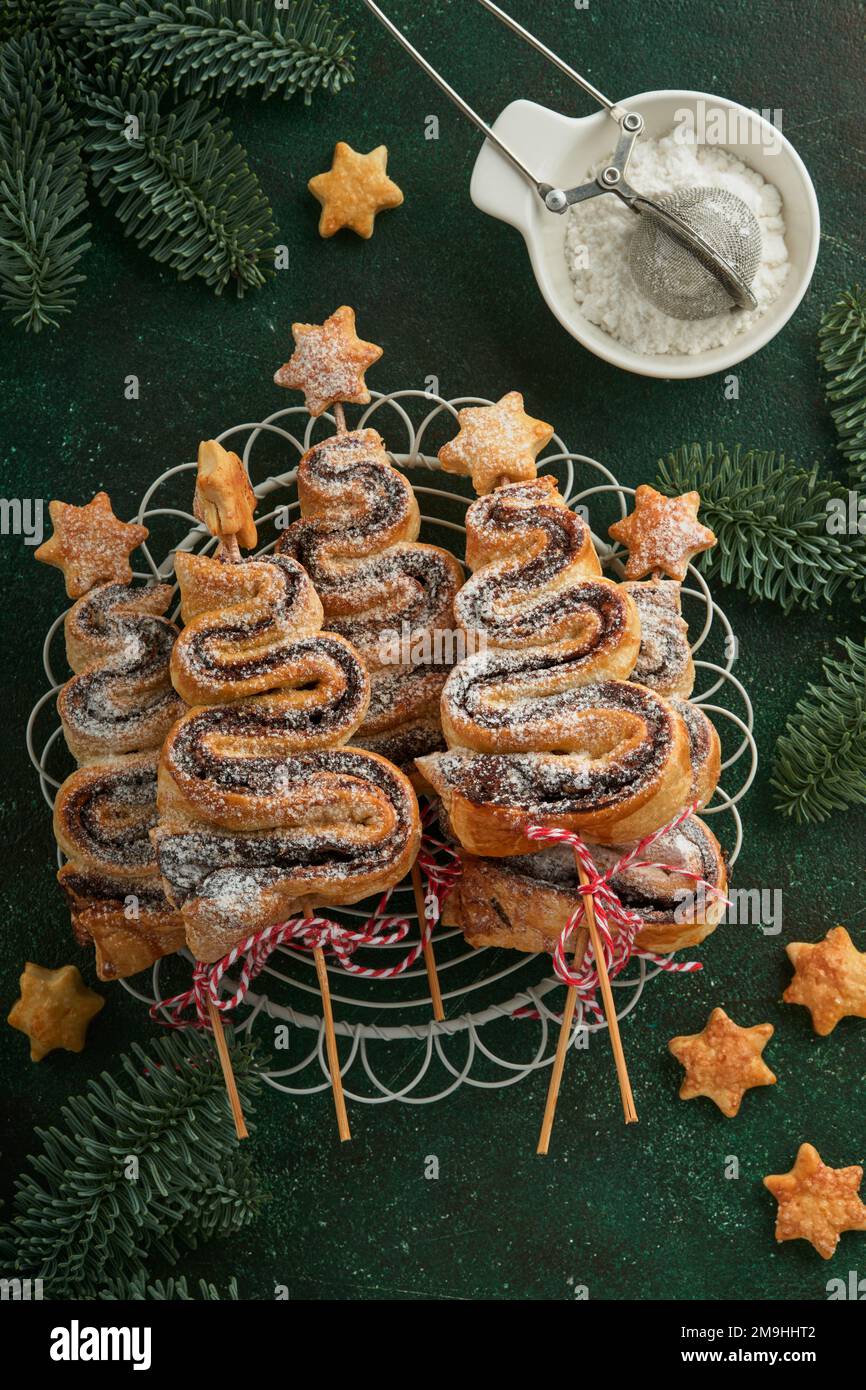 Gâteau feuilleté en forme d'arbre de Noël avec garniture au chocolat, poudre de sucre et sucettes sur fond vert ancien. Noël, hors-d'œuvre du nouvel an. Fest Banque D'Images