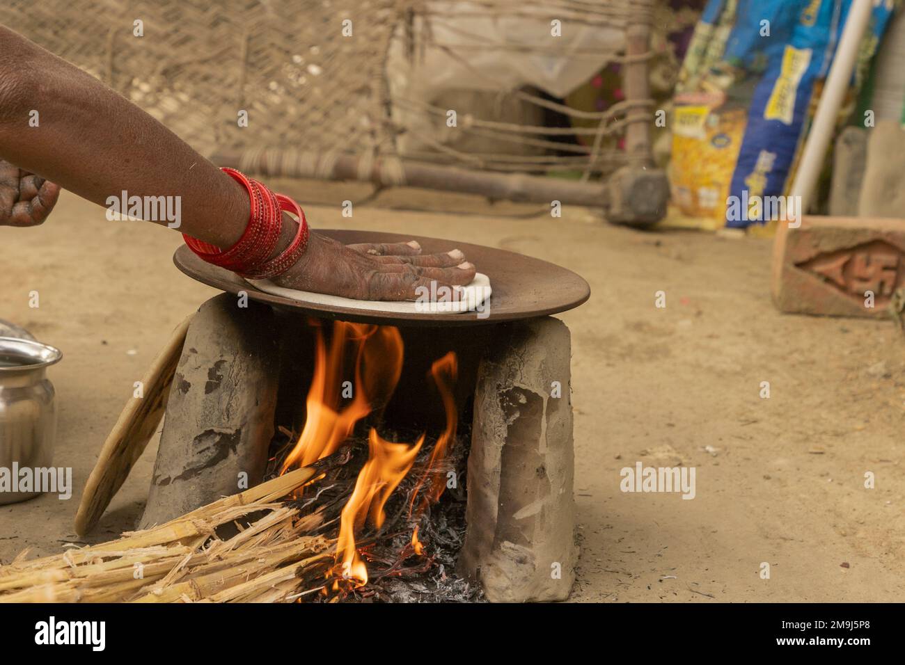 Un pain de riz (litti/bhakri) est fait sur un chulah/poêle traditionnel dans un village Banque D'Images