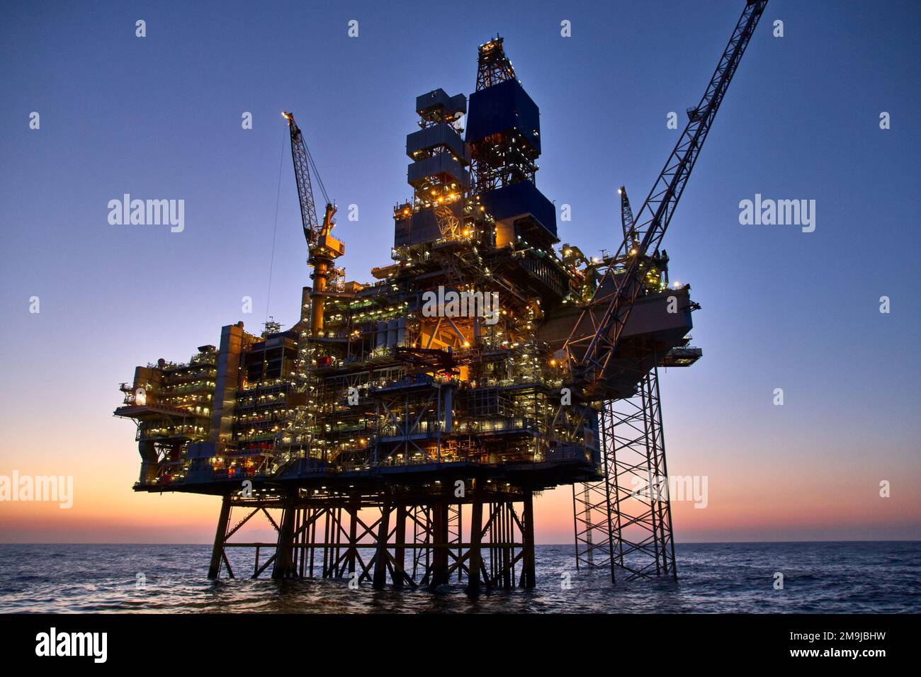 Jack up rig dans l'océan au coucher du soleil. Usine de production de pétrole brut dans la mer. Banque D'Images