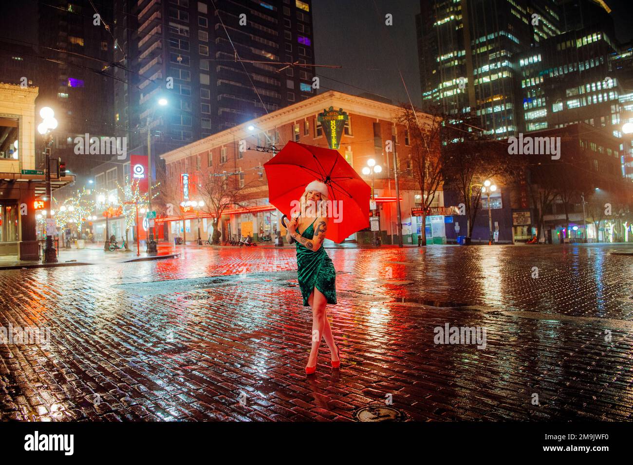 Femme à chapeau de Santa avec parapluie dans la rue, Seattle, Washington, États-Unis Banque D'Images