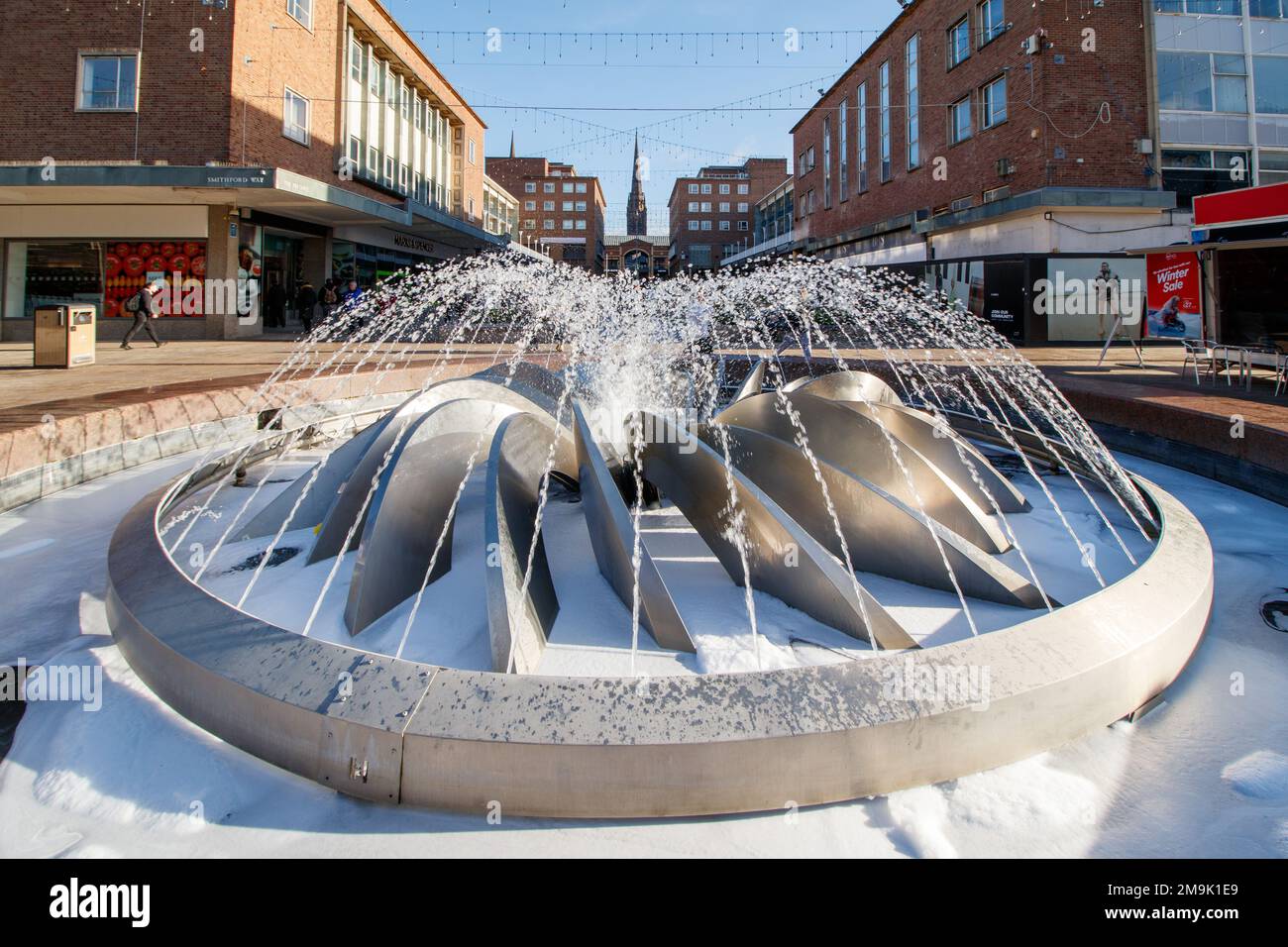 La fontaine de la pièce maîtresse de Smithford Way dans le centre de Coventry entre les quartiers supérieur et inférieur. L'ensemble de la zone a été rénové pour la ville de Culture 2021. La vue de la fontaine donne sur la partie supérieure du quartier vers la flèche de l'église de la Sainte Trinité au loin. Banque D'Images