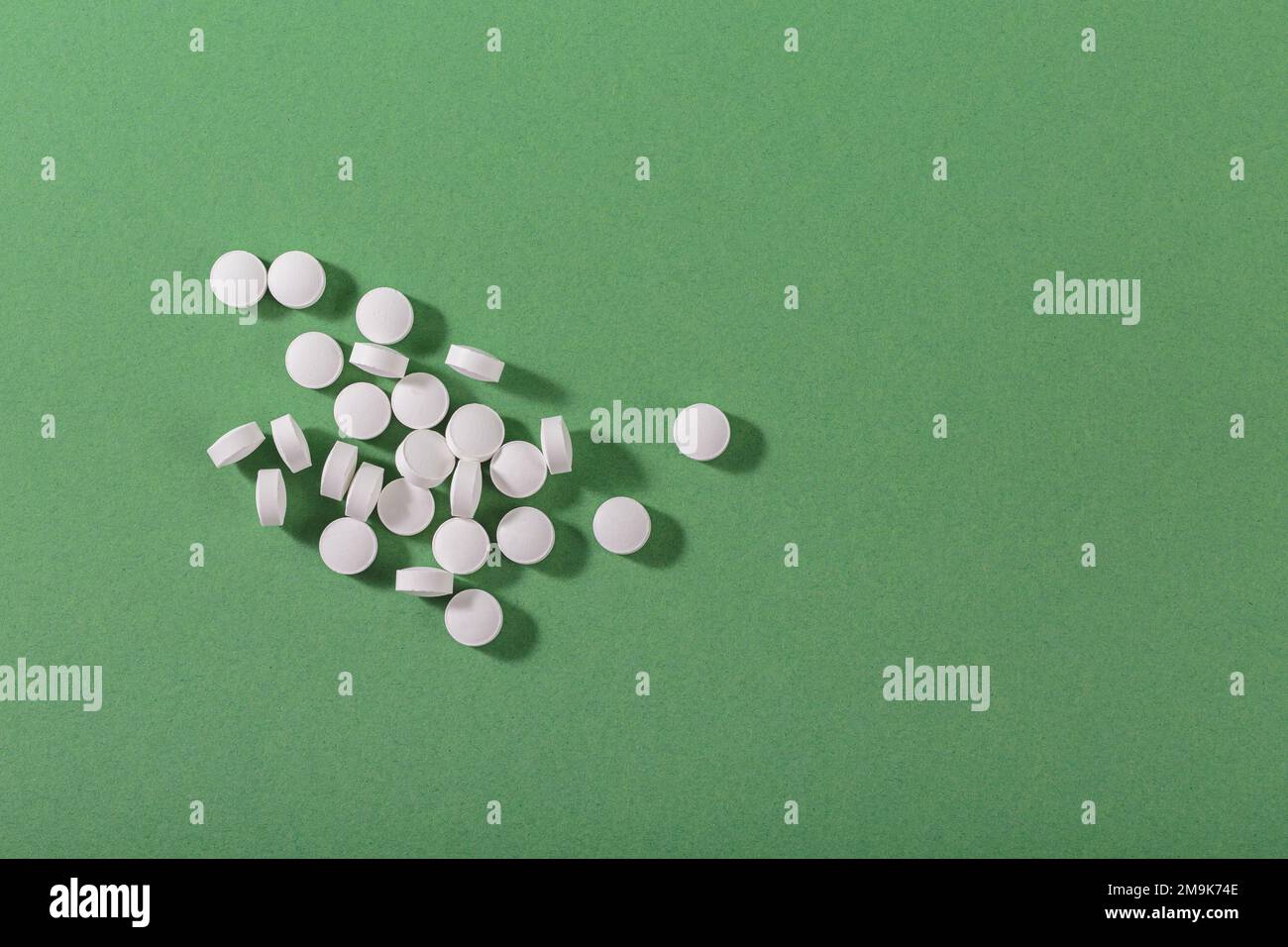 Pilules blanches de fines herbes et de vitamine nourriture saine librement posée sur fond vert Banque D'Images