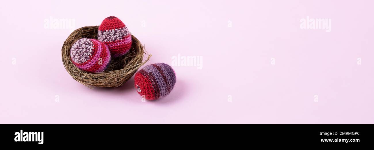Trois oeufs décoratifs de Pâques tricotés dans des tons lilas et pourpres dans un nid sur un fond violet. Concept joyeuses Pâques. Carte de vœux avec une copie de t Banque D'Images