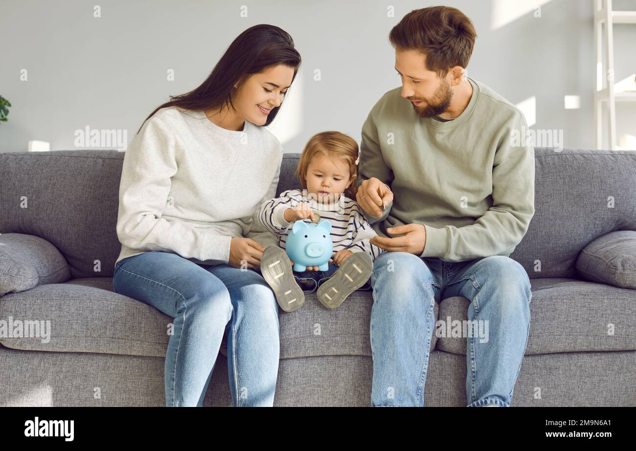 Des parents souriants apprennent à leur bébé comment économiser de l'argent Banque D'Images