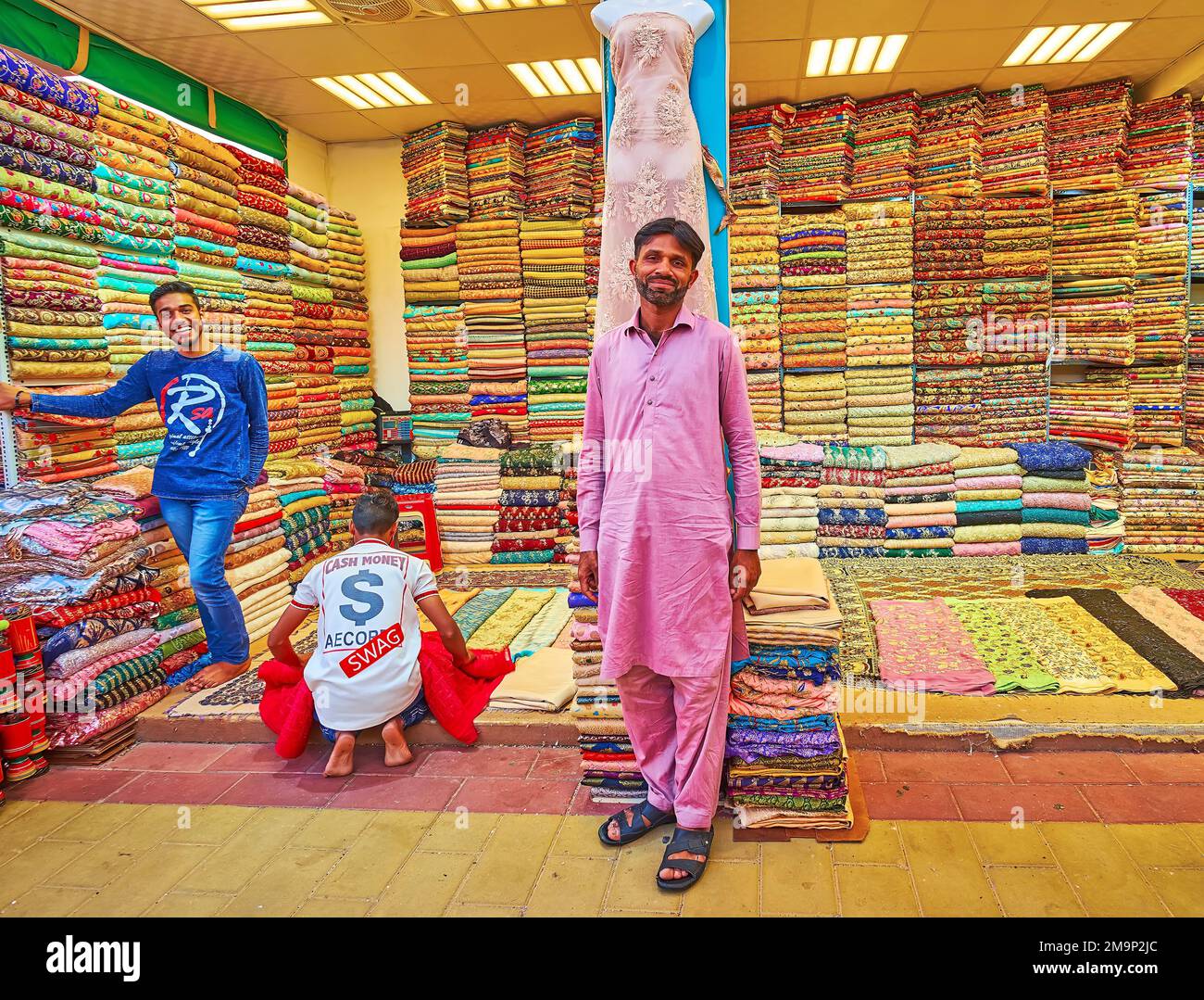 DUBAÏ, Émirats Arabes Unis - 6 MARS 2020 : le commerçant souriant devant son magasin de textile sur le marché du tissu du Pavillon du Pakistan, village mondial de Dubaï, sur 6 mars Banque D'Images