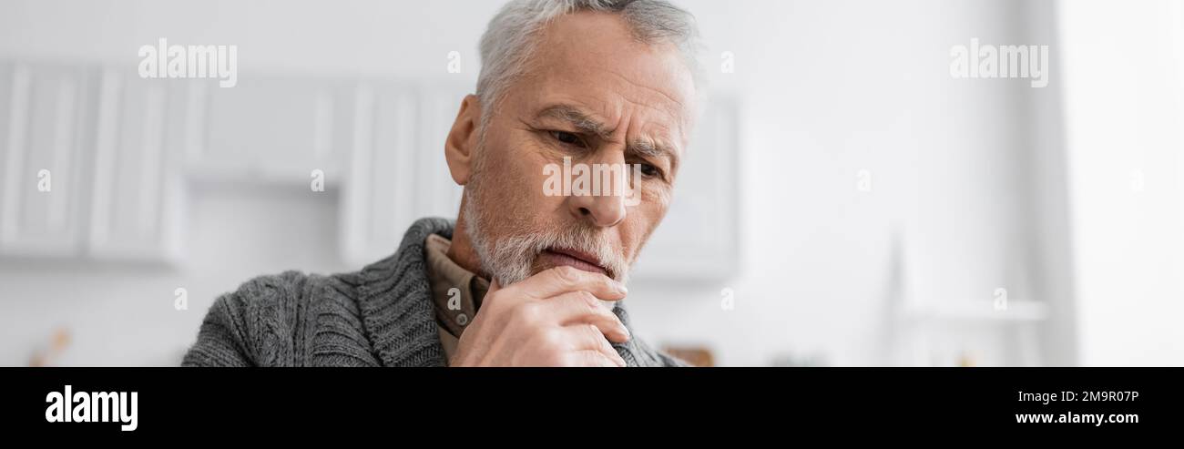 homme âgé pensif avec la maladie d'alzheimer tenant la main près du menton tout en pensant à la maison, bannière, image de stock Banque D'Images