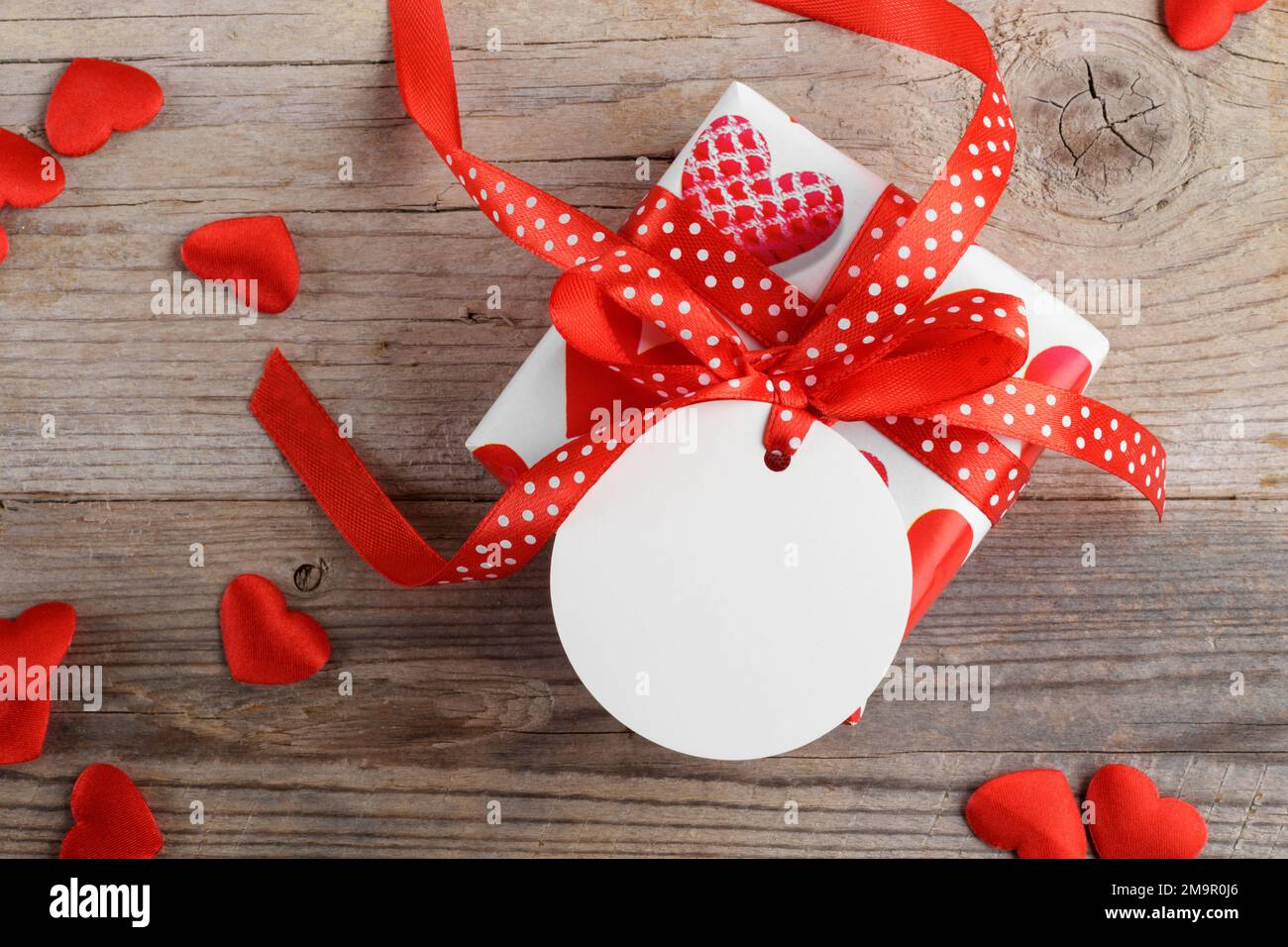 Cadeau de Saint-Valentin avec étiquette cadeau ronde blanche maquette sur fond rustique en bois avec coeur rouge Banque D'Images