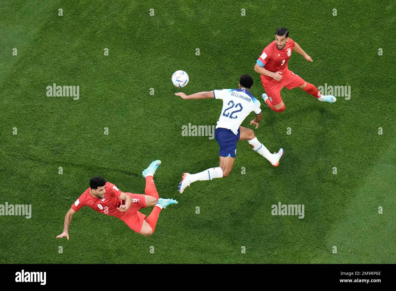 England's Jude Bellingham, center, fights for the ball with Iran's Mehdi Taremi, left, and Iran's Mehdi Taremi during the World Cup group B soccer match between England and Iran at the Khalifa International Stadium in in Doha, Qatar, Monday, Nov. 21, 2022. (AP Photo/Hassan Ammar) Banque D'Images