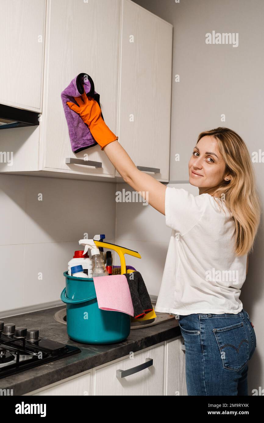 La femme de ménage essuie la cuisine avec un chiffon en microfibre