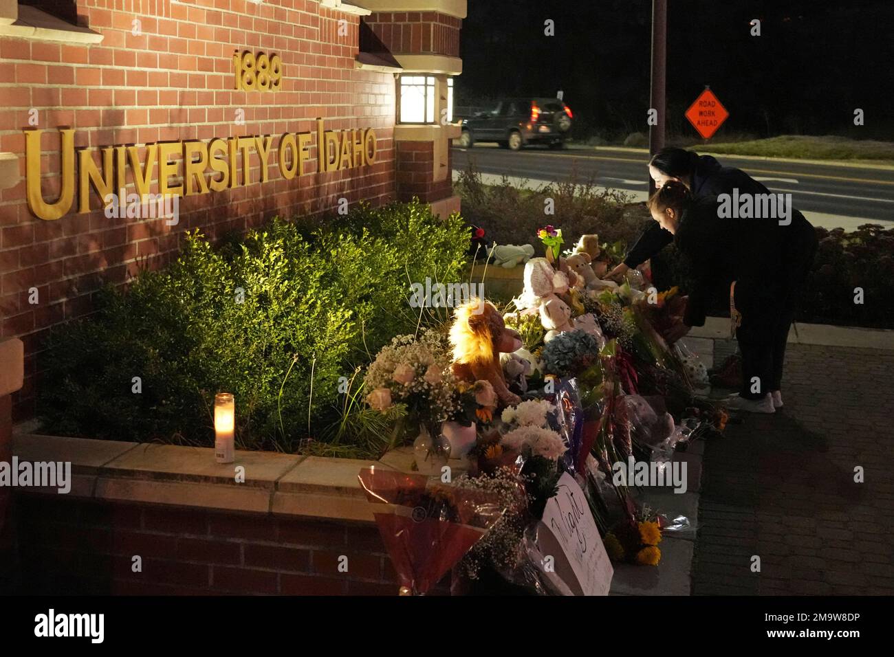 Two people place flowers at a growing memorial in front of a campus entrance sign for the University of Idaho, Wednesday, Nov. 16, 2022, in Moscow, Idaho. Four University of Idaho students were found dead on Sunday, Nov. 13, 2022, at a residence near campus. (AP Photo/Ted S. Warren) Banque D'Images