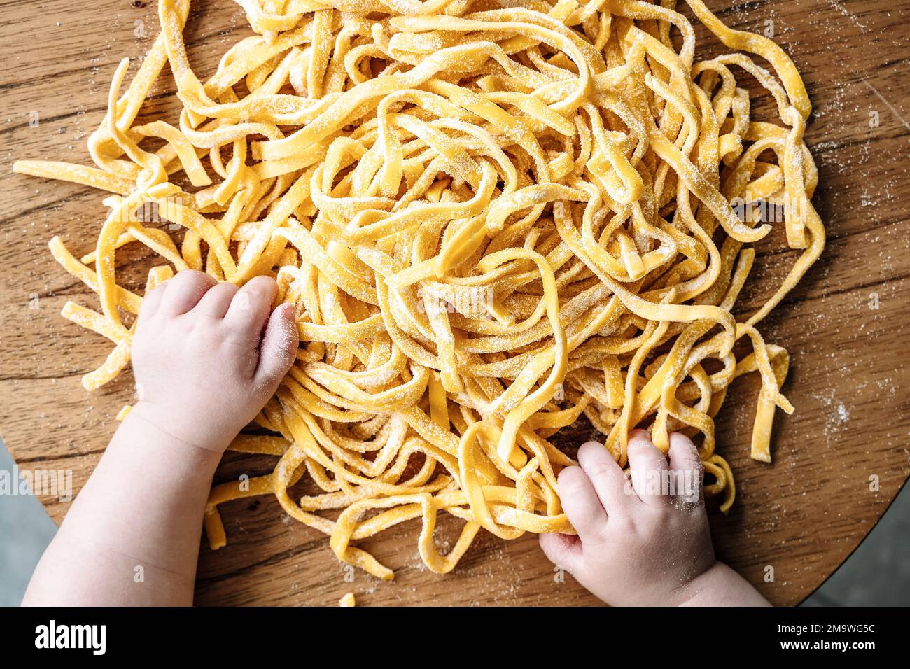 Pâtes et enfant. Bébé cuisine des pâtes fraîches italiennes dans la cuisine maison. Nourriture et enfants concept. Photo de haute qualité Banque D'Images