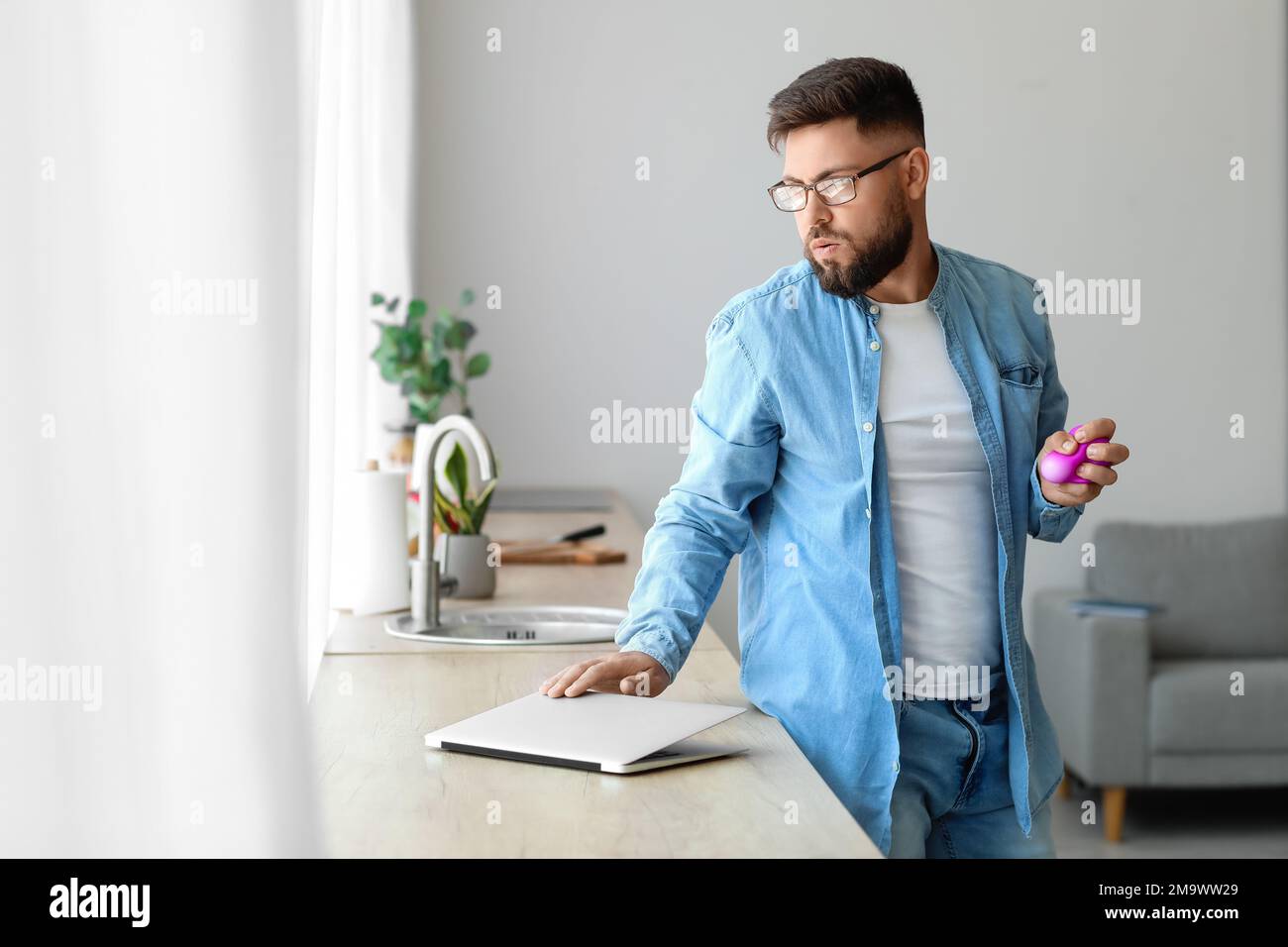 Un jeune homme stressé se met à presser le ballon à la maison Banque D'Images