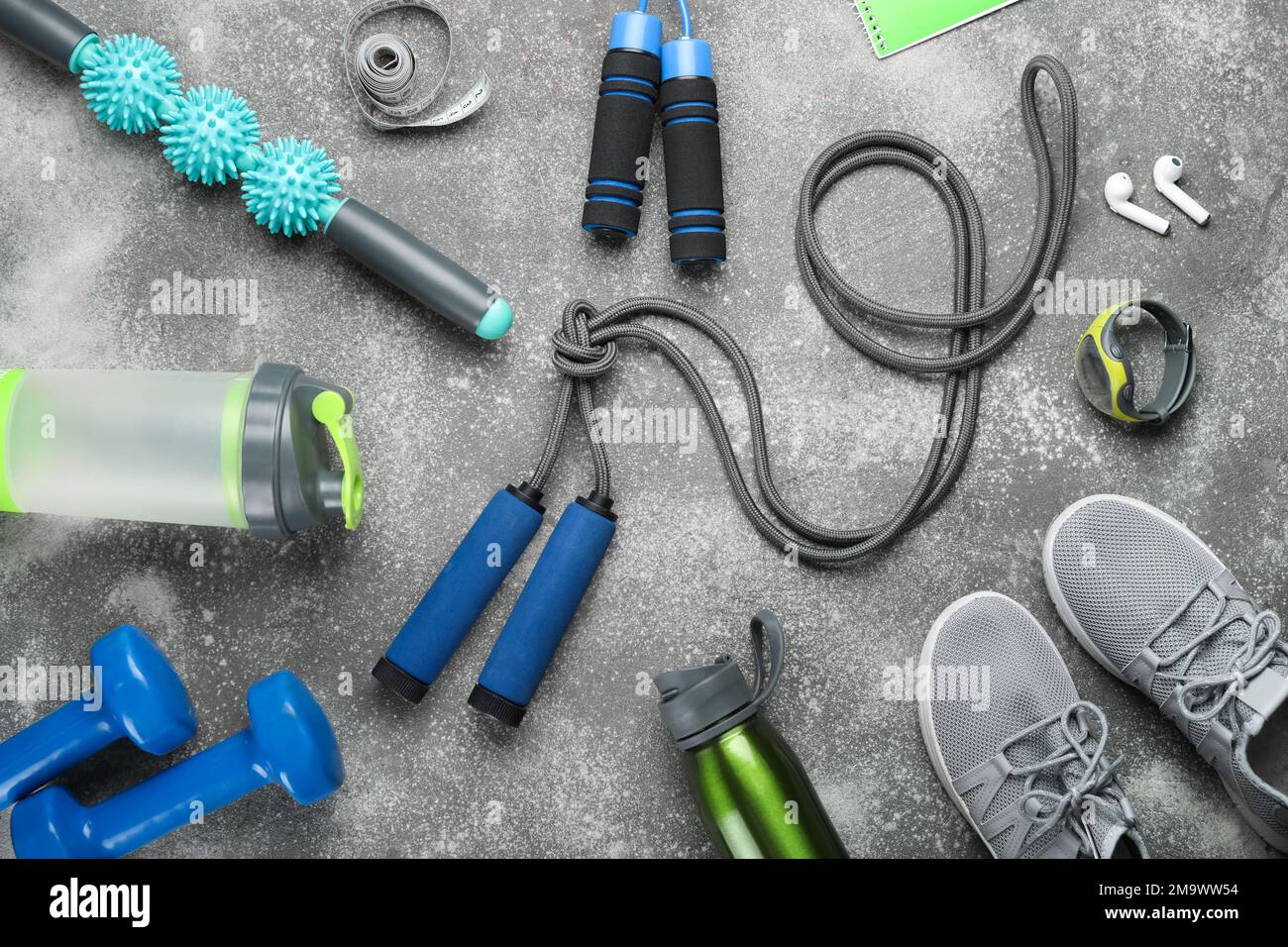 Cordes à sauter avec des équipements de sport, des bouteilles, du ruban de mesure et des baskets sur fond sombre Banque D'Images