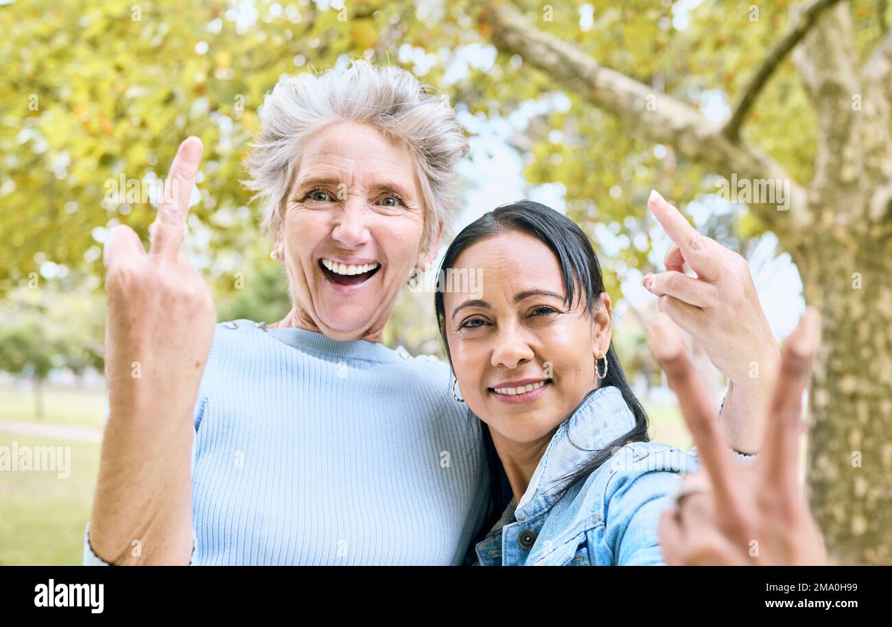 Femmes âgées, portrait de parc et signe de main pour le comique, drôle et heureux temps ensemble dans la nature. Vieille femme, amis et mains avec la paix, le doigt du milieu Banque D'Images