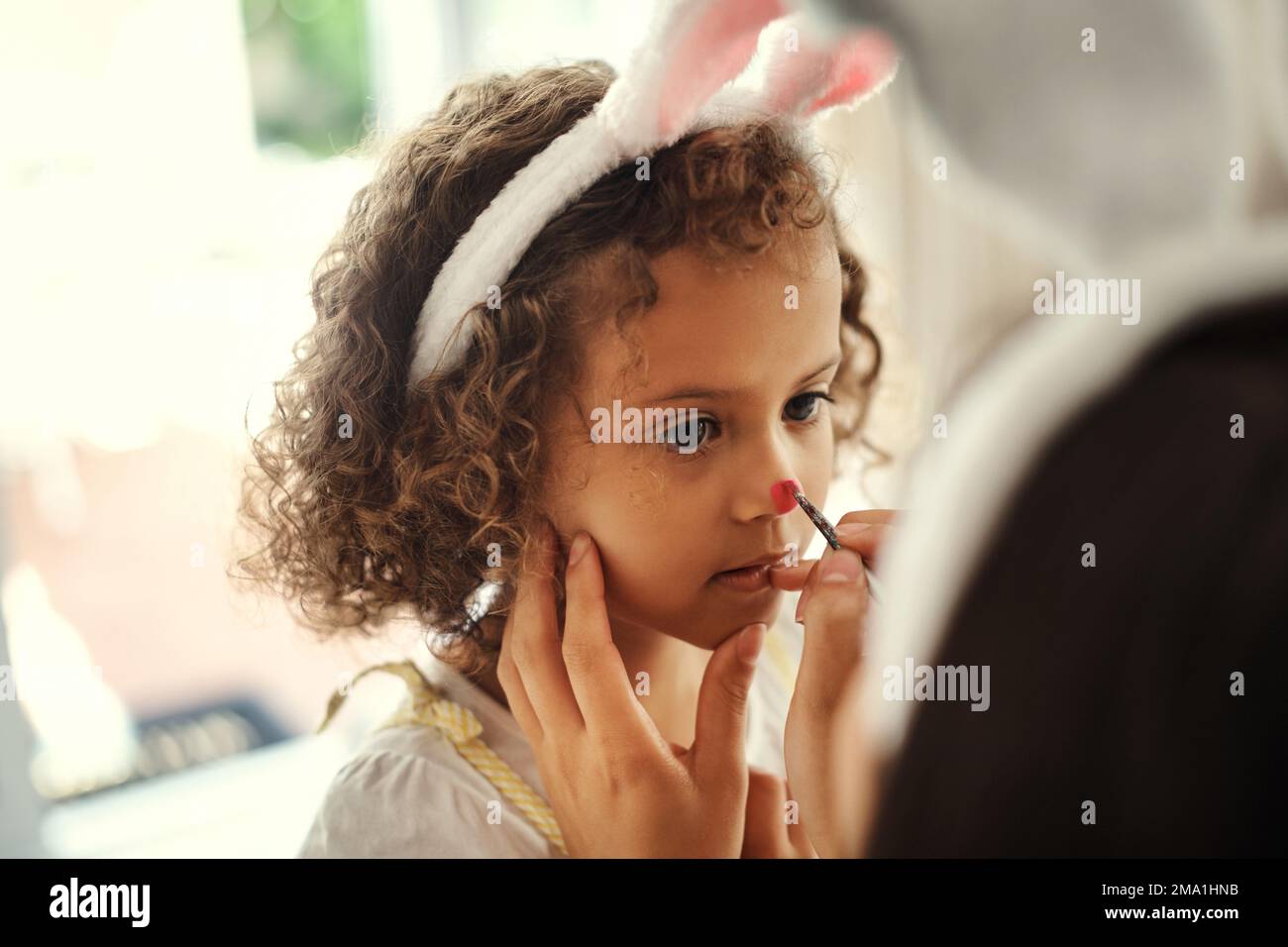 Voulez-vous un nez rouge ? une femme peint le visage de ses filles pendant les vacances de pâques. Banque D'Images