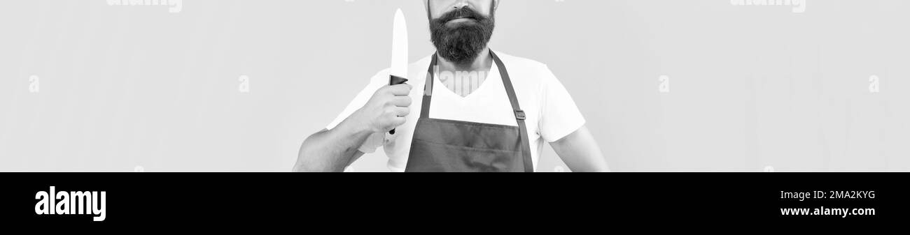 Vue sur les récoltes de l'homme sérieux dans un tablier rouge tenant les chefs couteau fond jaune, chef Banque D'Images