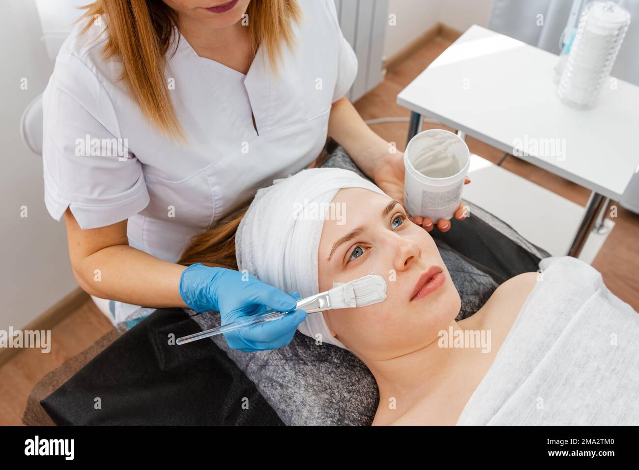 Mains de spécialiste en cosmétologie appliquant un masque facial Banque D'Images