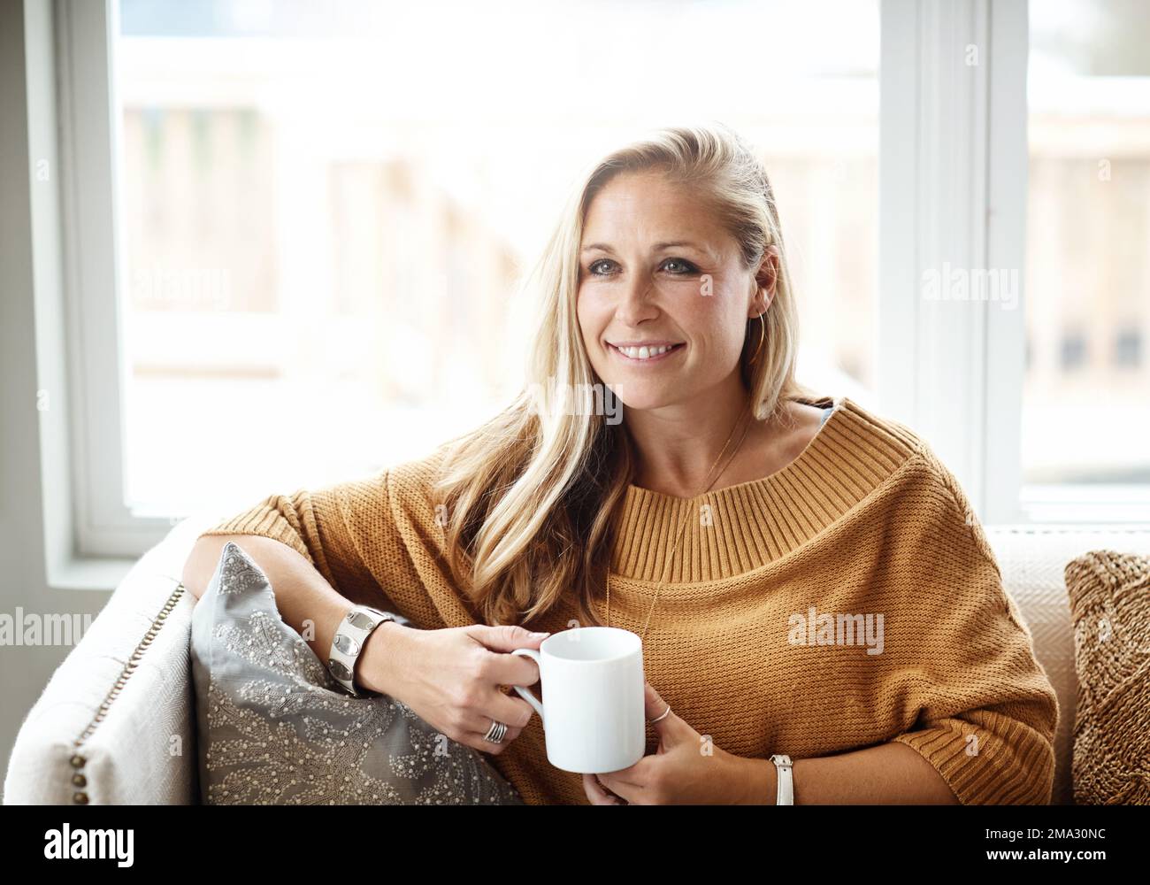 Femme, penser et se détendre heureux avec le thé sur le canapé dans la salle de séjour pour la tranquillité d'esprit du matin, vision calme et la planification des idées de style de vie dans la maison Banque D'Images
