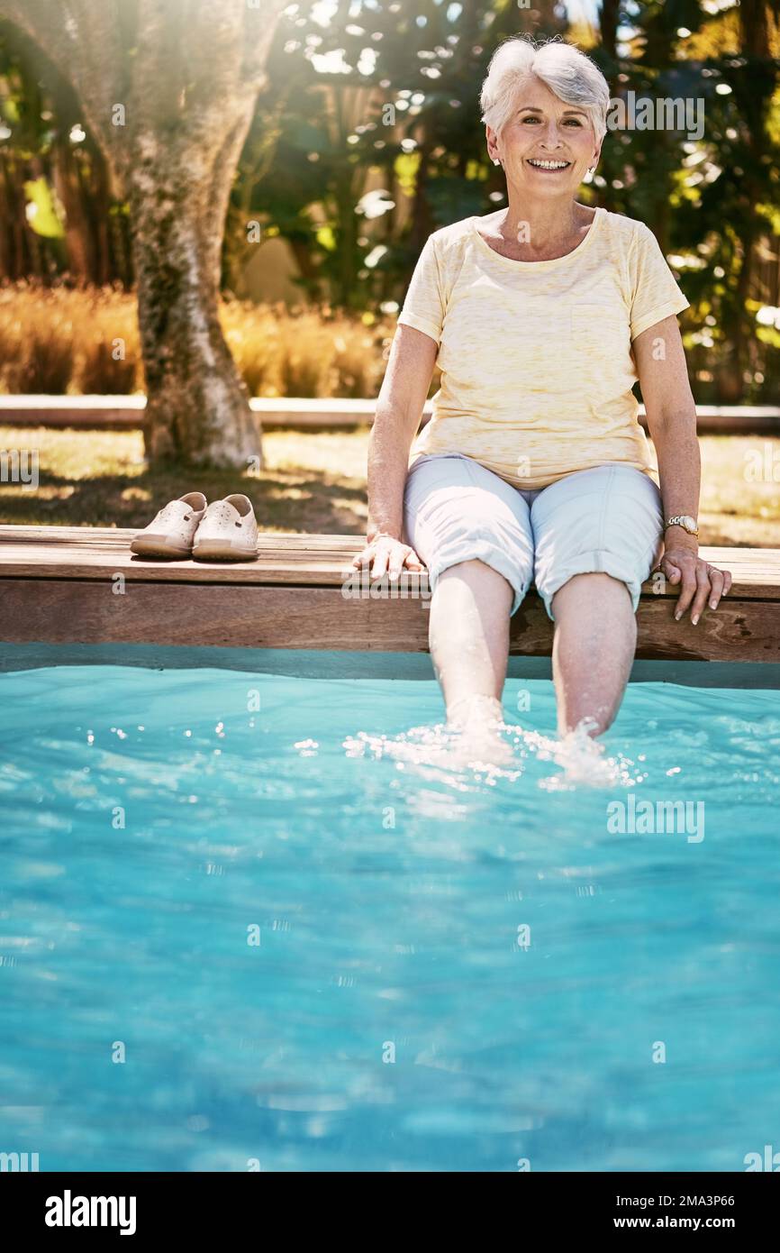Détendez-vous, femme âgée et piscine de pieds dans un portrait heureux avec le sourire et le temps amusant sur les vacances de retraite. Été, soleil et vieille dame avec des jambes dans l'eau Banque D'Images