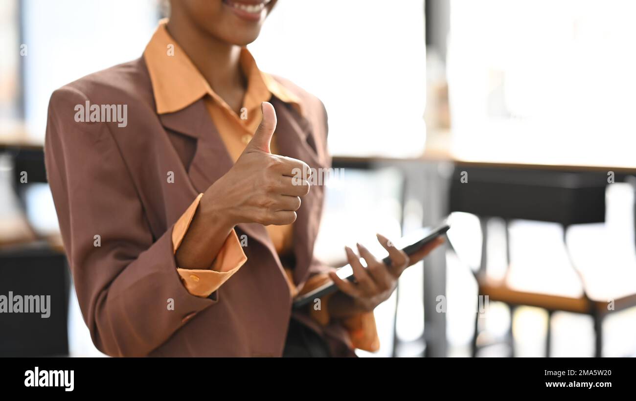 Image rognée Go businesswoman dans un costume élégant tenant une tablette et montrant les pouces vers le haut Banque D'Images