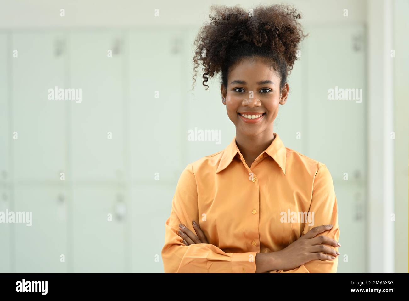 Portrait d'une employée africaine américaine debout avec des bras croisés et souriant à l'appareil photo Banque D'Images