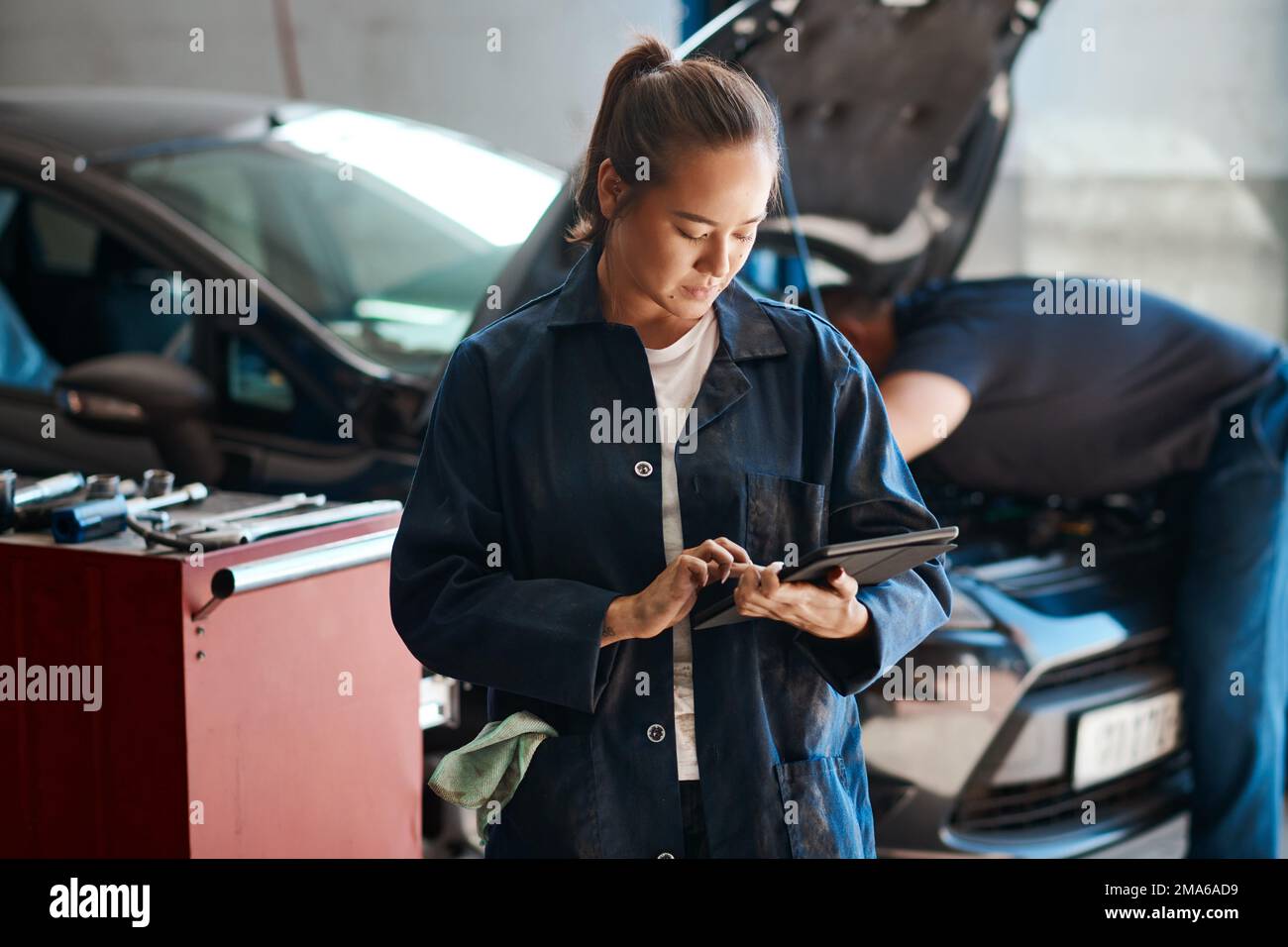 Nous utilisons les outils de diagnostic les plus récents pour résoudre les problèmes. une femme mécanicien utilisant une tablette numérique tout en travaillant dans un atelier de réparation automobile. Banque D'Images