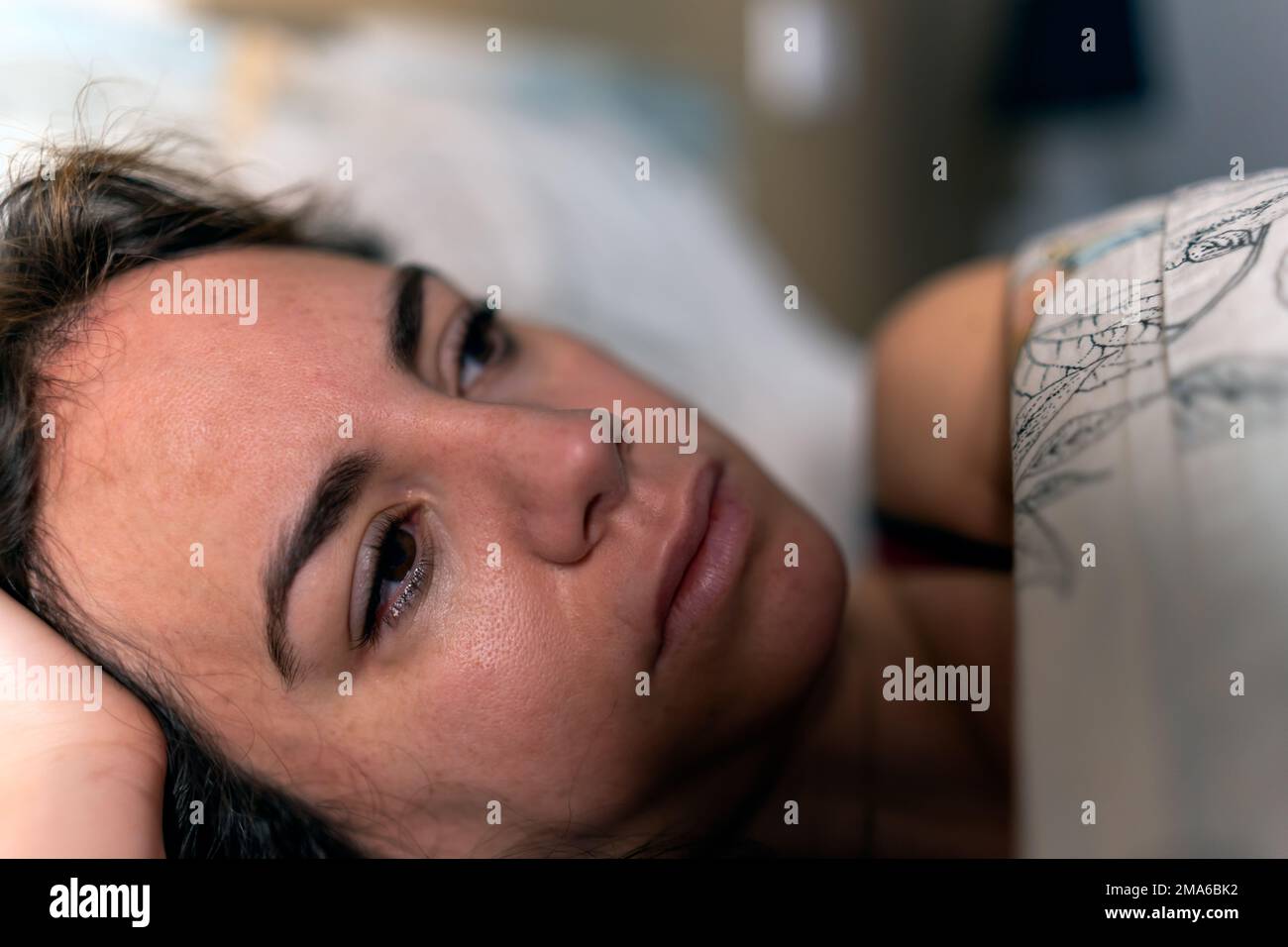 gros plan d'une jeune femme pensive avec des yeux tendus allongé sur un lit. Dépression et santé mentale Banque D'Images