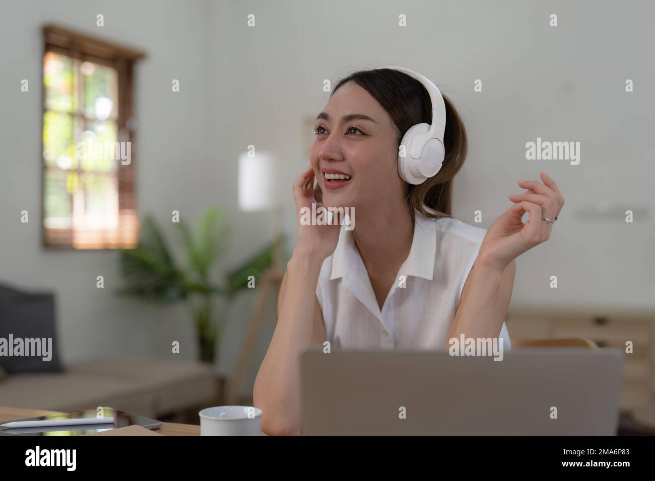Une jeune femme qui écoute de la musique en ligne porte des écouteurs sans fil et profite de la chanson préférée. Liste de lecture, application musique Banque D'Images